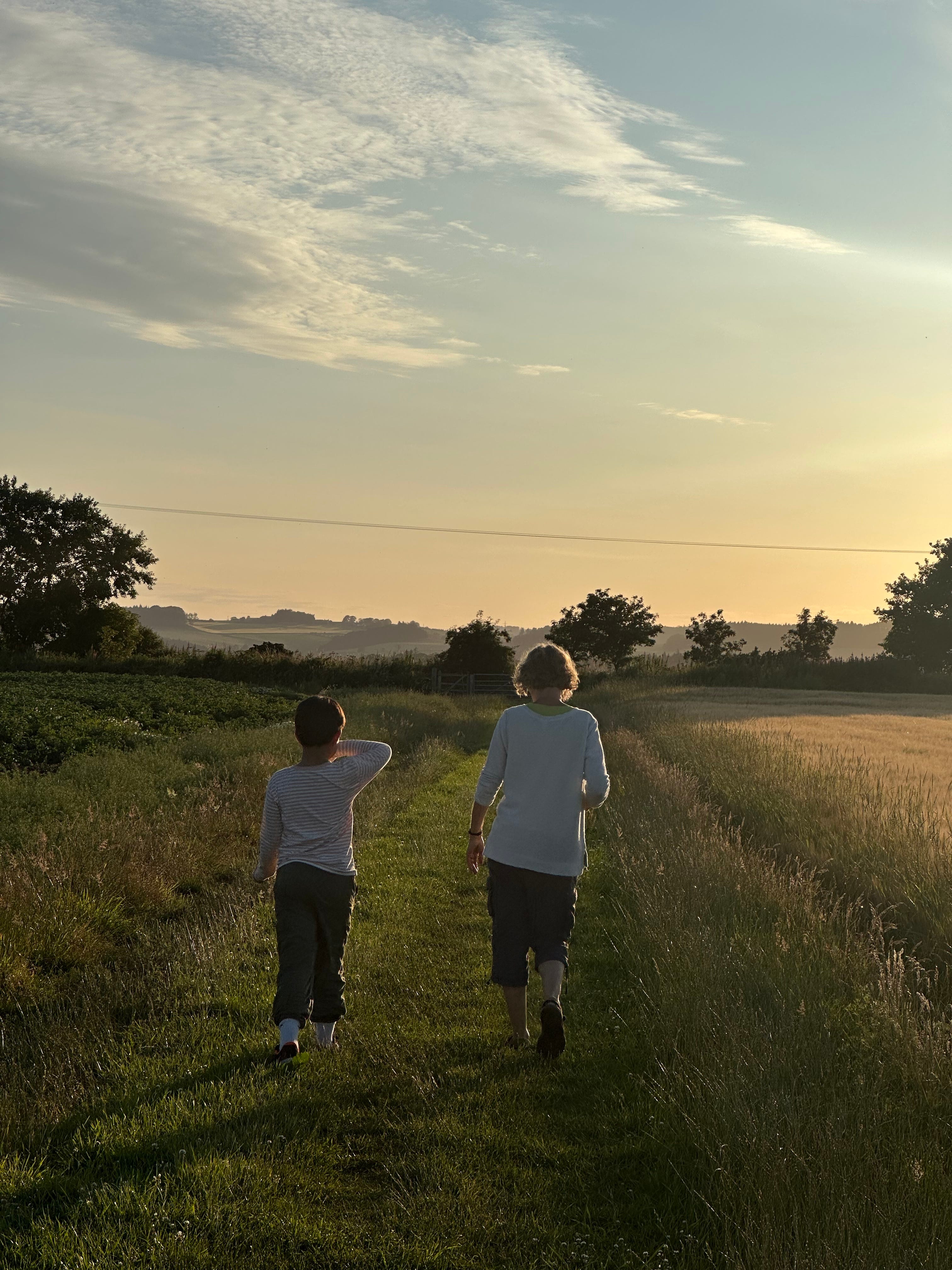 Boy and woman walking through a field in Scotland.