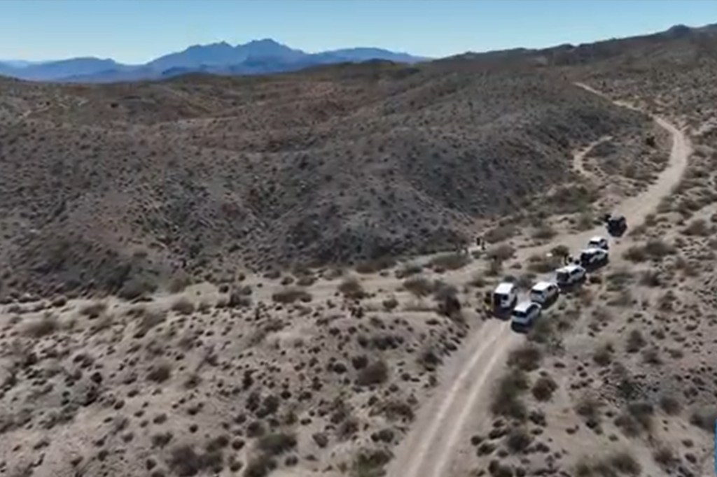 Aerial view of a desert area with a dirt road and several vehicles, likely during the investigation of human remains outside Las Vegas.