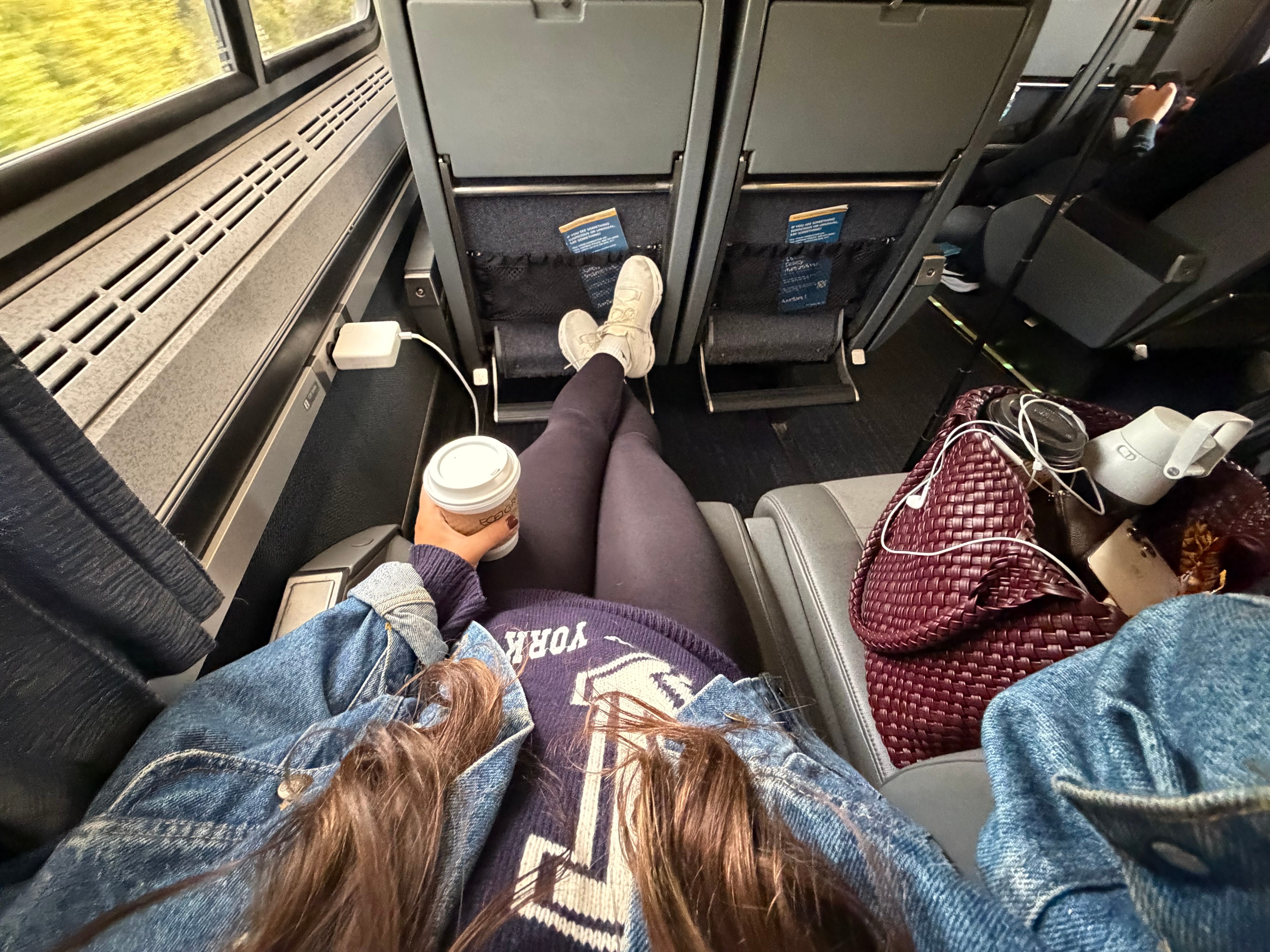Amanda stretching out on an Amtrak, with her legs on the leg-rest in front of her.