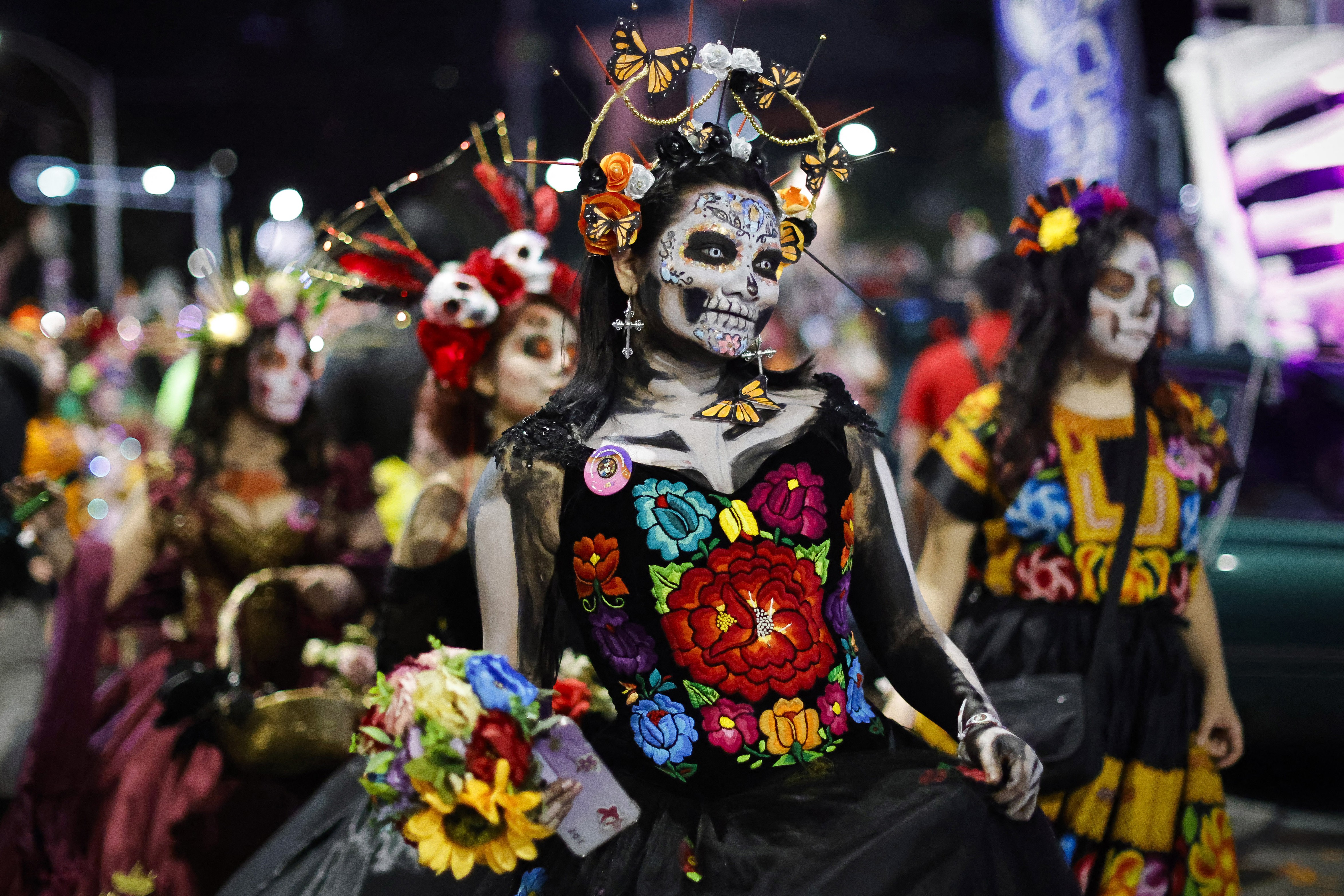 A parade of people dressed as traditional skull-faced Catrinas.