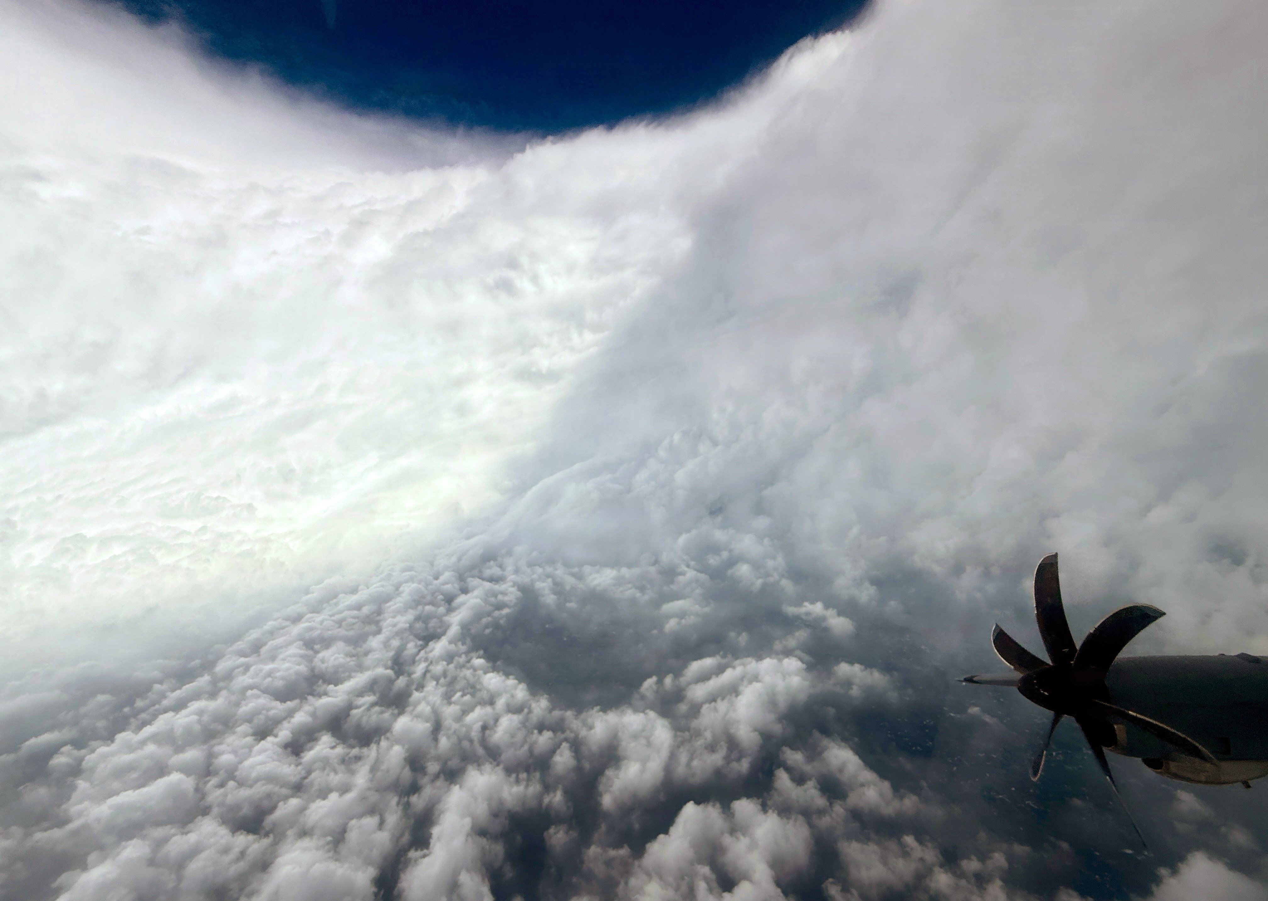 A view from an airplane of the interior of the eye of a hurricane—an empty space surrounded by massive curved walls of swirling clouds