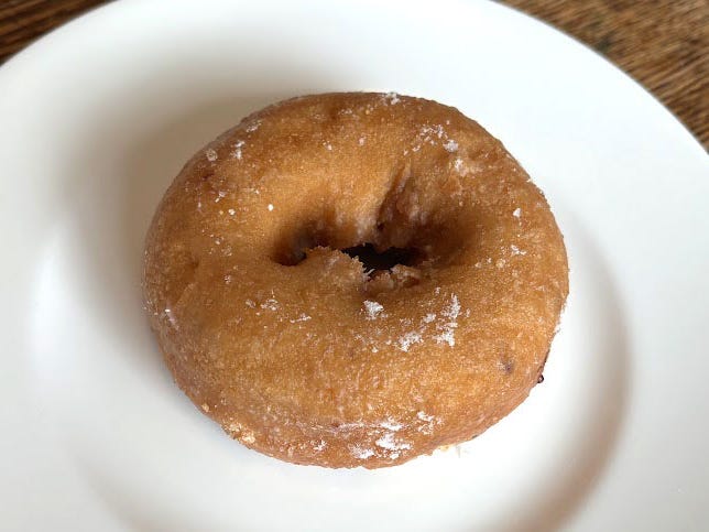 A blueberry doughnut on a white plate.