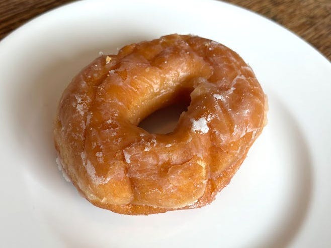 A glazed doughnut on a white plate.