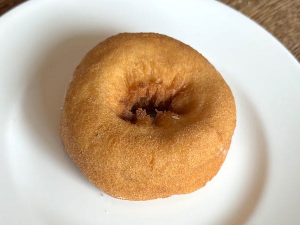 A plain cakey doughnut on a white plate.