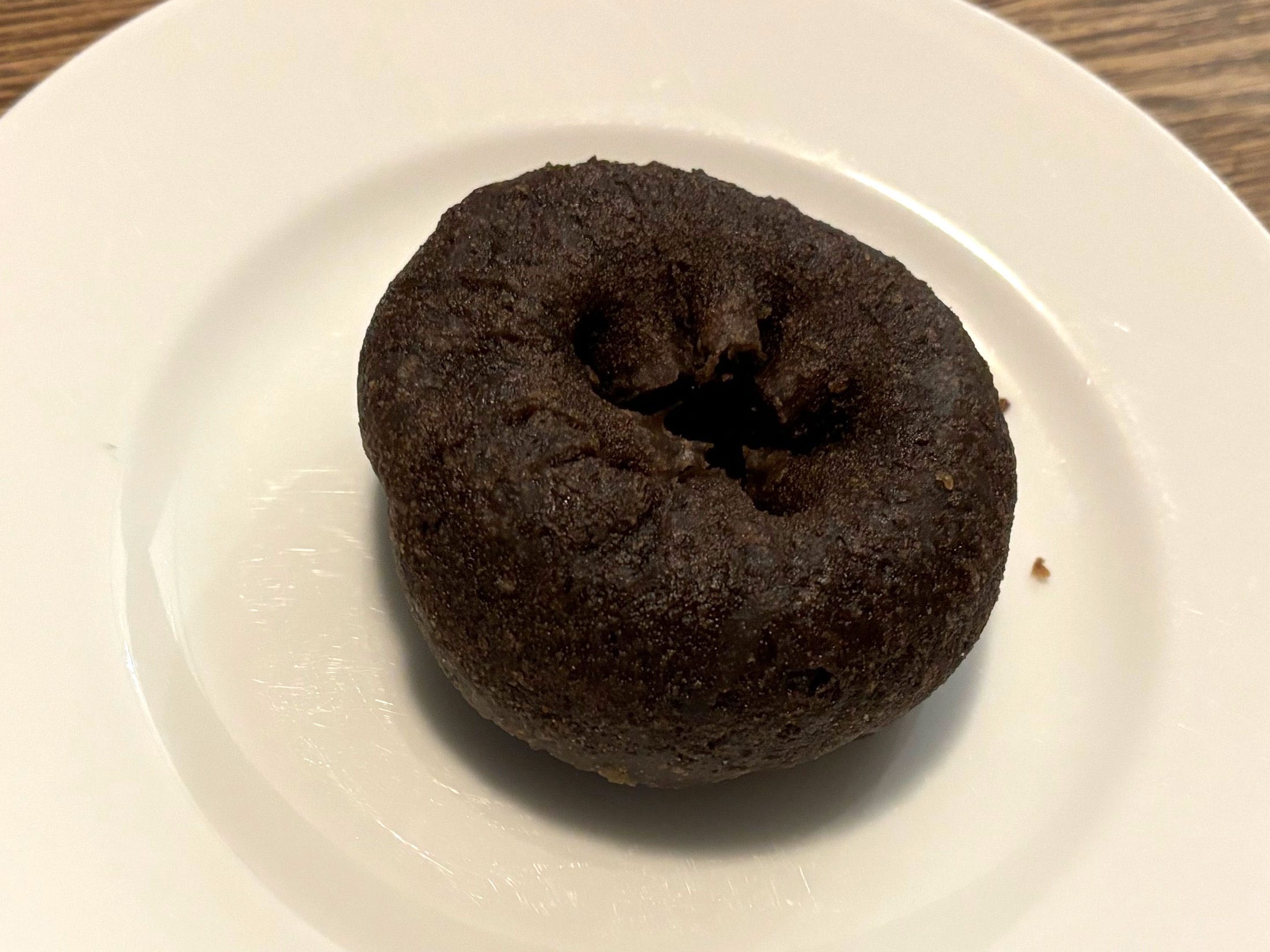 A chocolate-cake doughnut on a white plate.