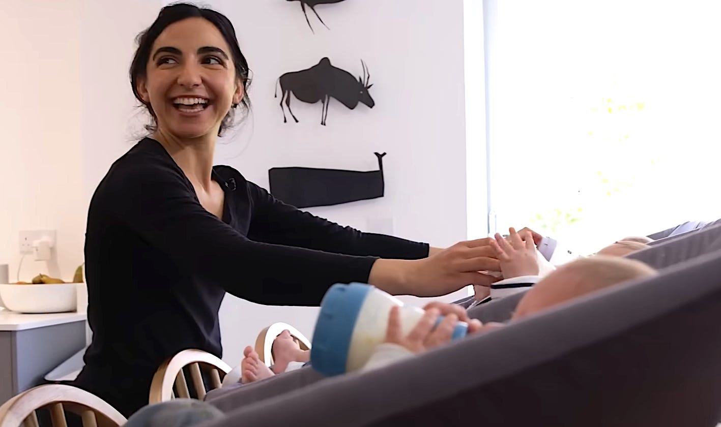 Woman in black caring for three babies, triplets.
