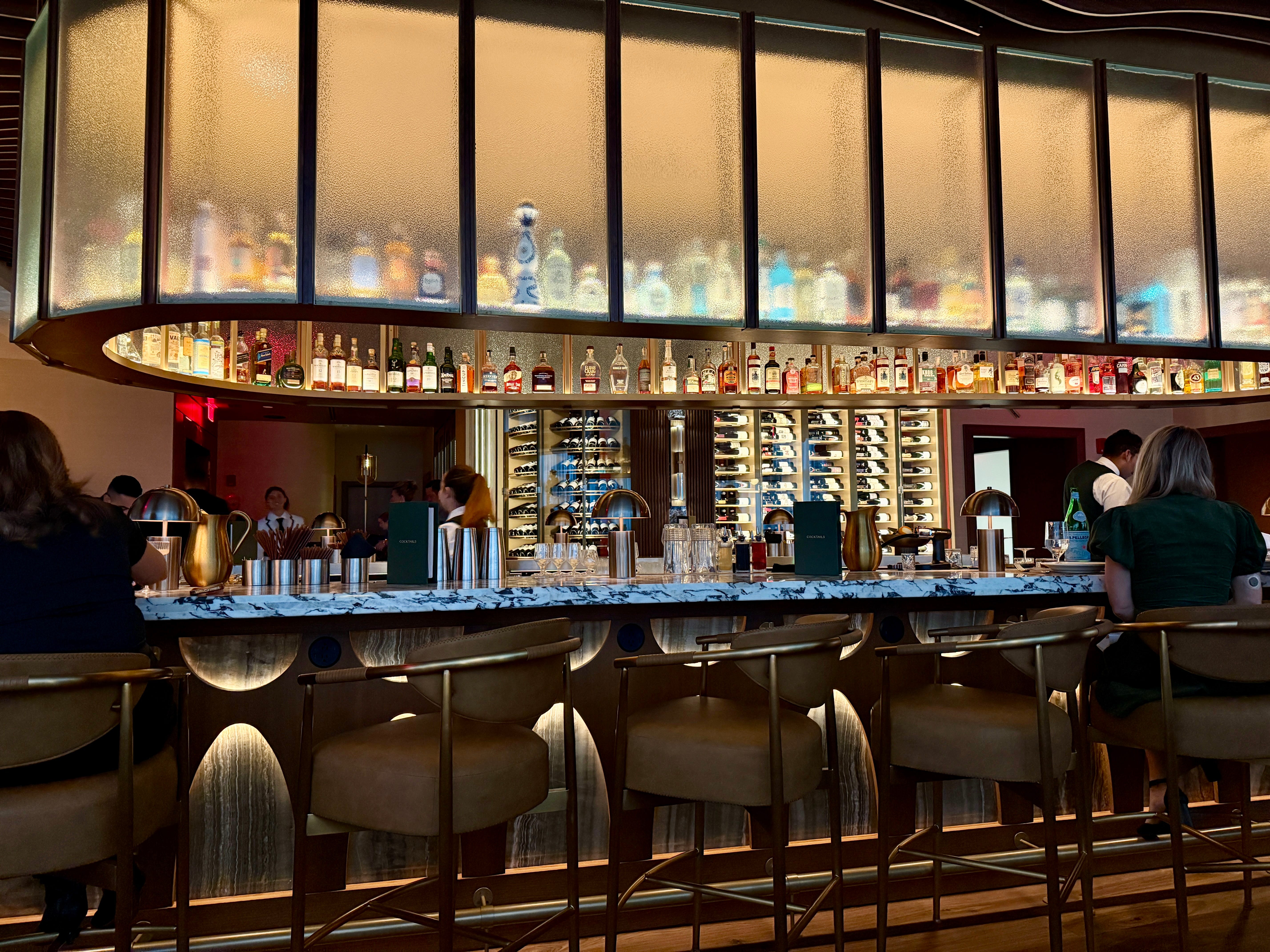 Marble-toppde bar with fabric and metal stools in front of it at 1587 Prime