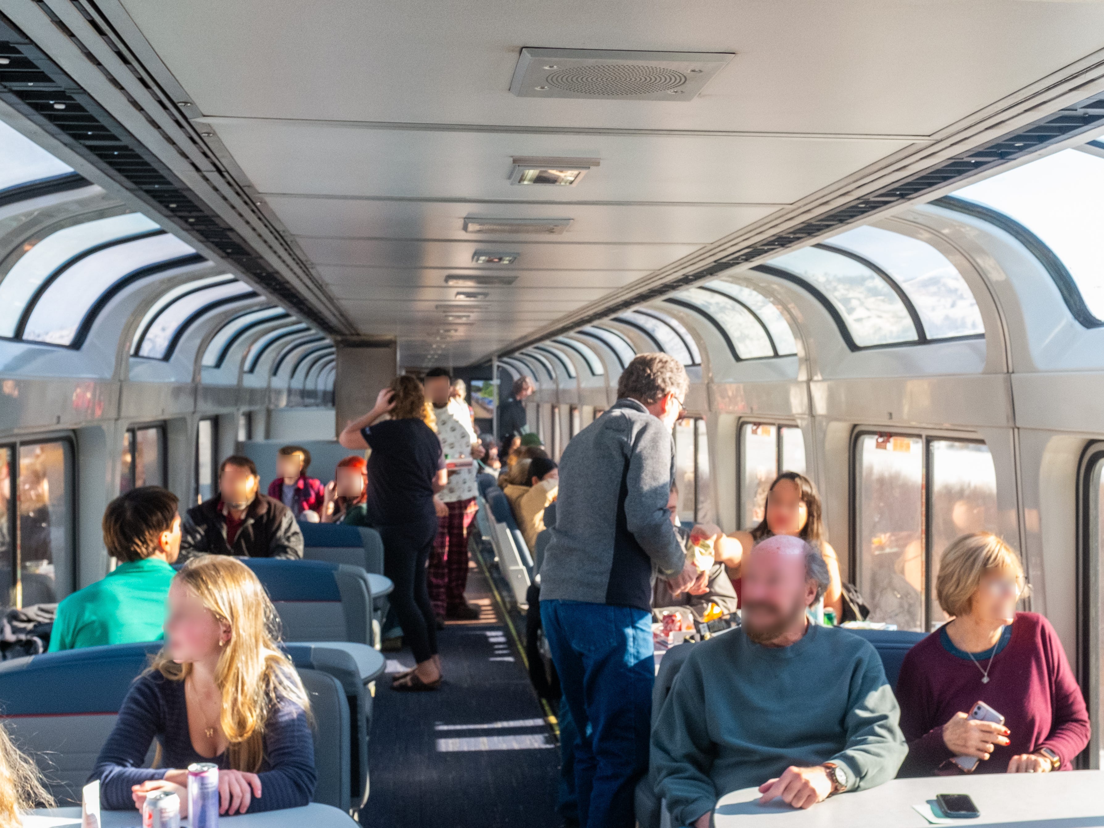 Passengers inside a full train car with two rows of windows on either side.