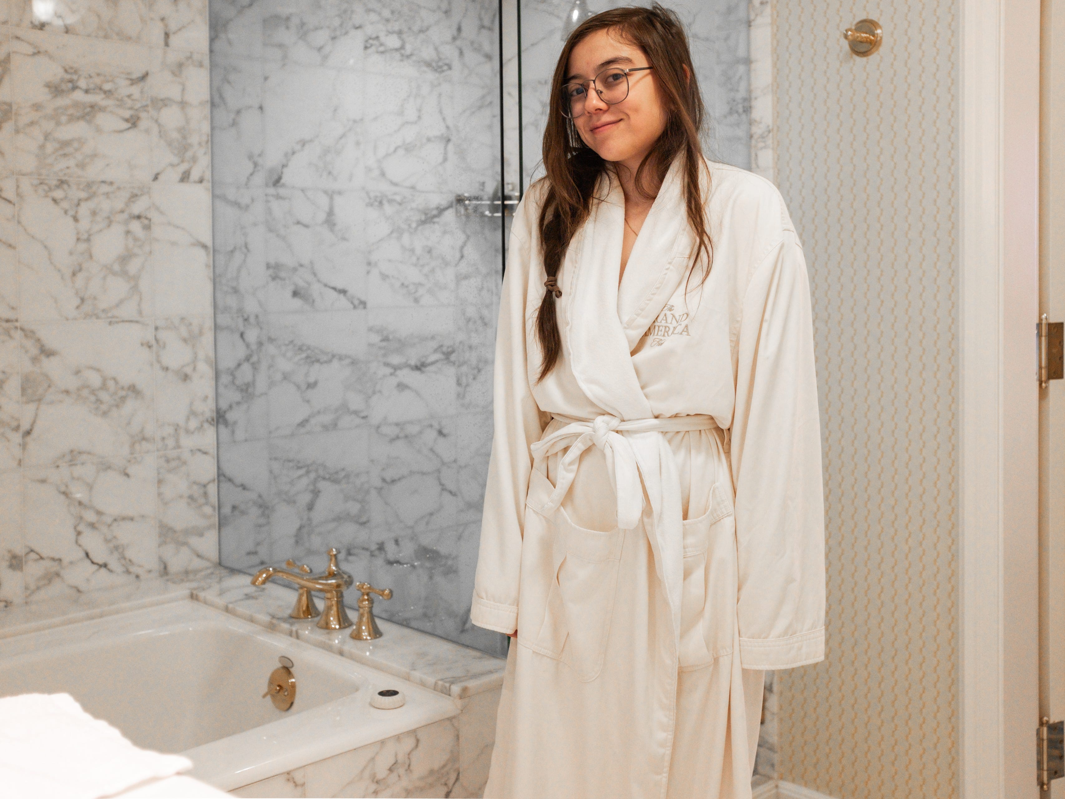 The author in a hotel robe stands in a marble bathroom