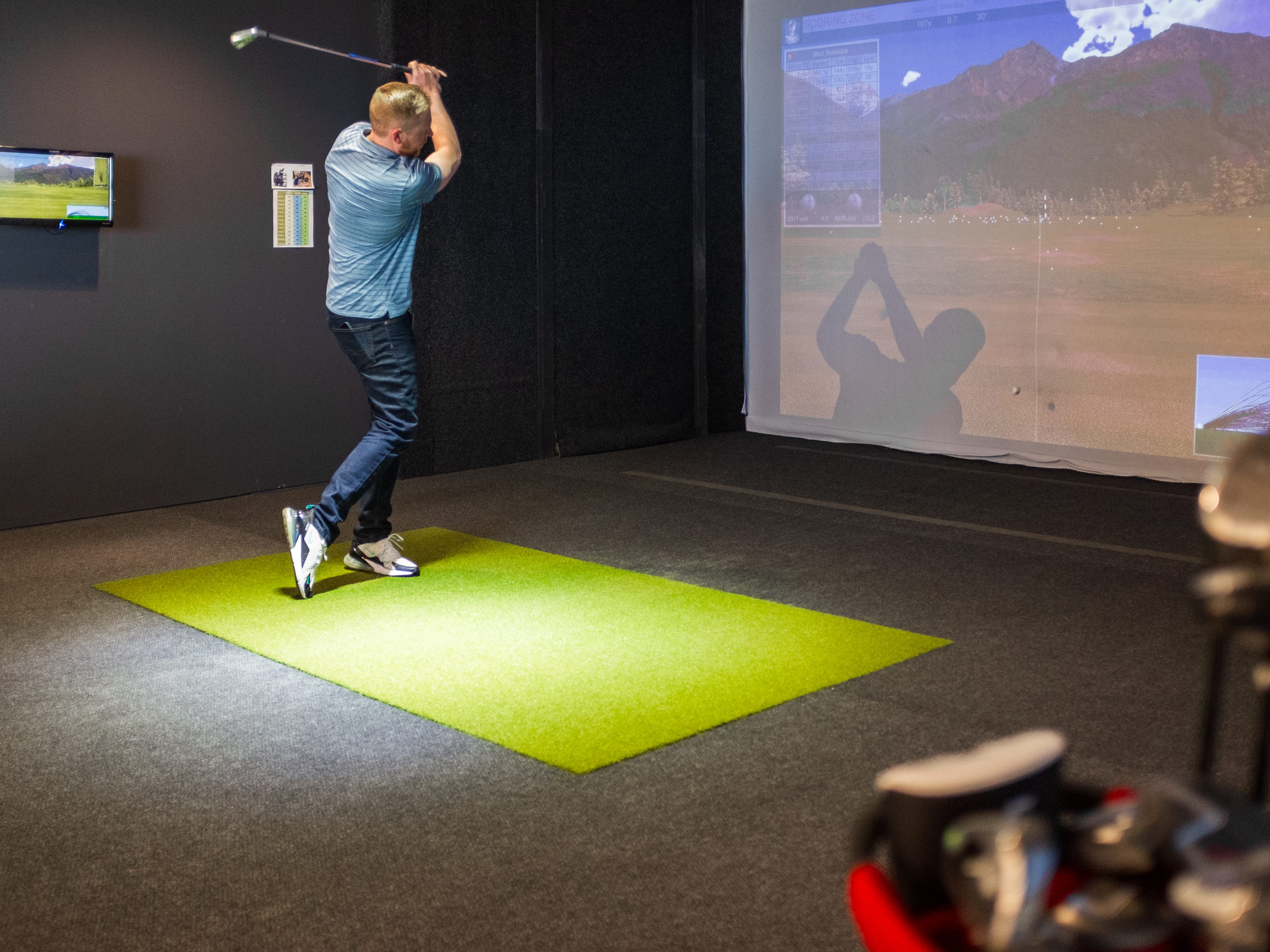 A tech worker swings a club in a virtual golf simulator