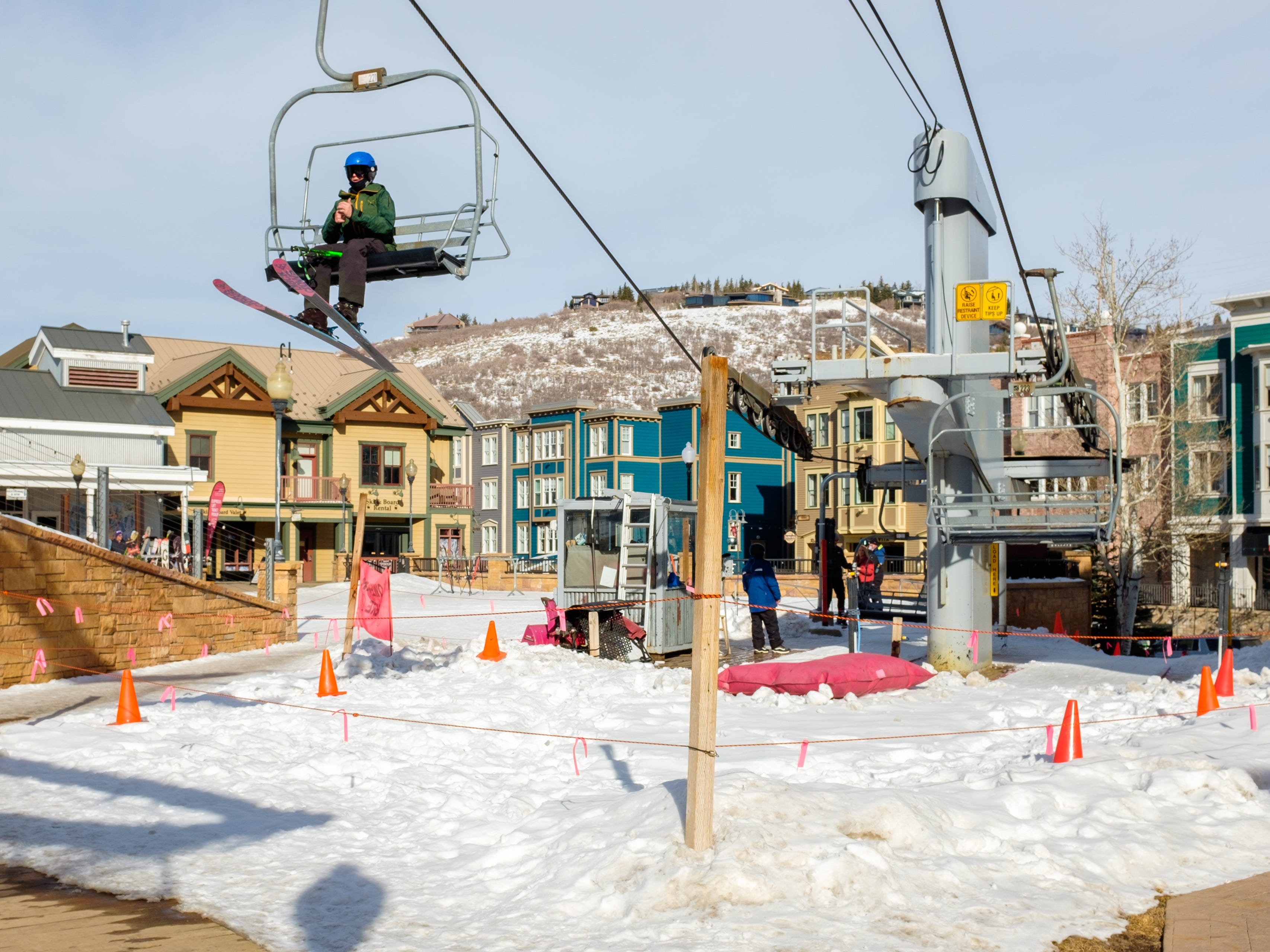 A skier on a lift above a snow-covered downtown area