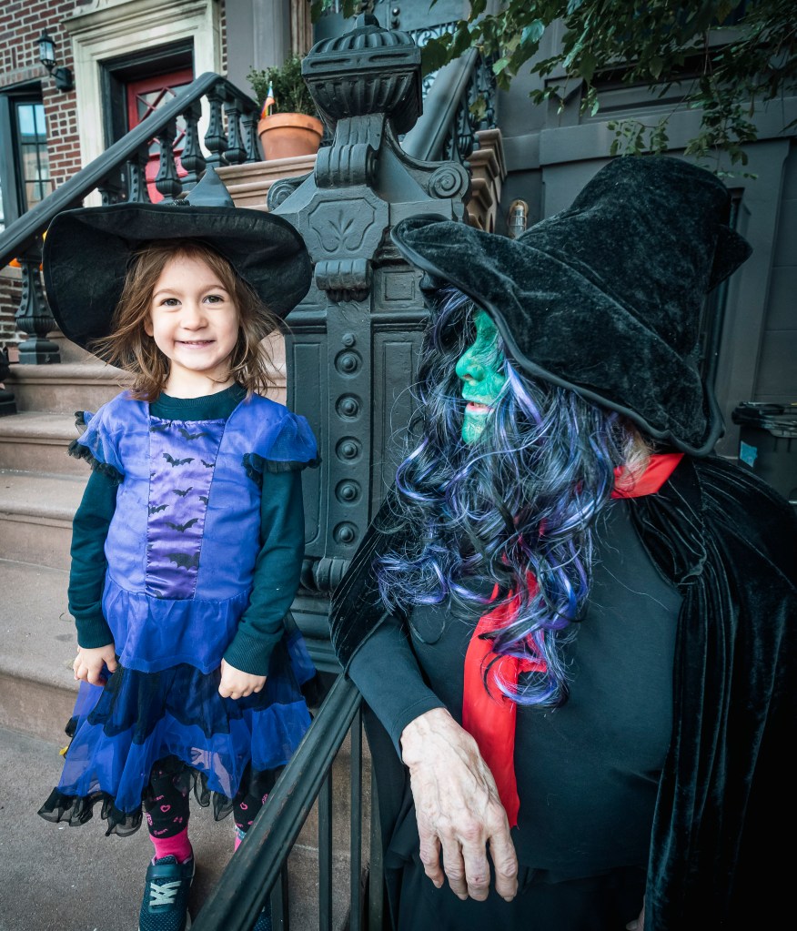 Sally Krause dressed as a witch on Halloween with a young girl in a witch costume.