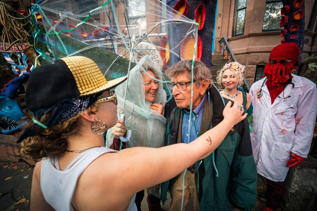 People in Halloween costumes with colorful decorations in the background.