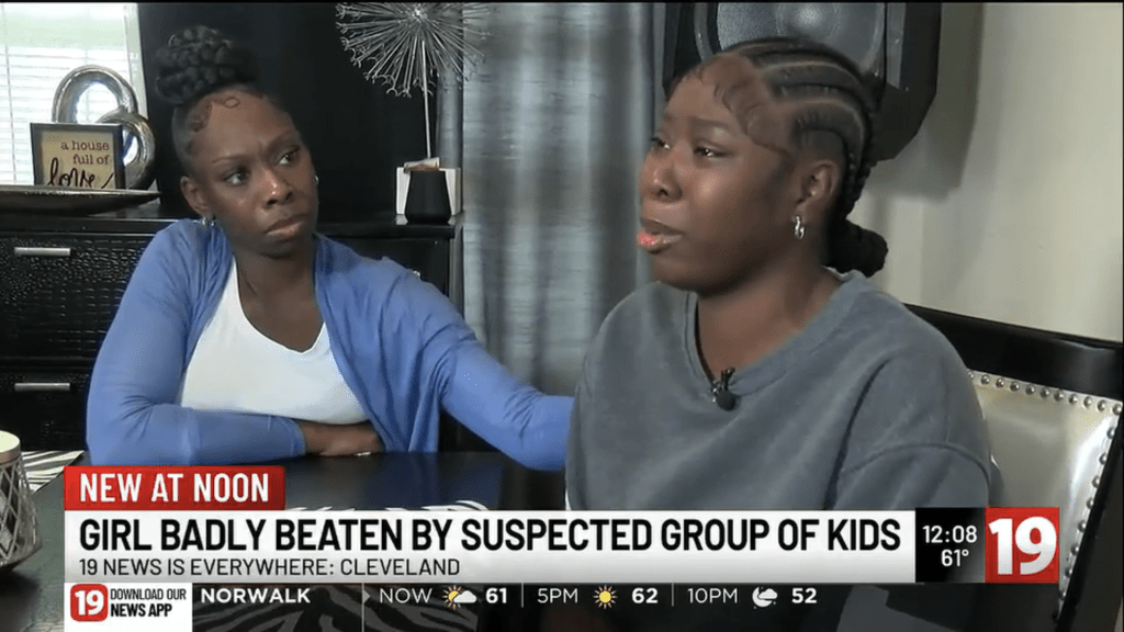 Two women, one with an arm around the other, discuss a girl being beaten by suspected kids on a news broadcast.