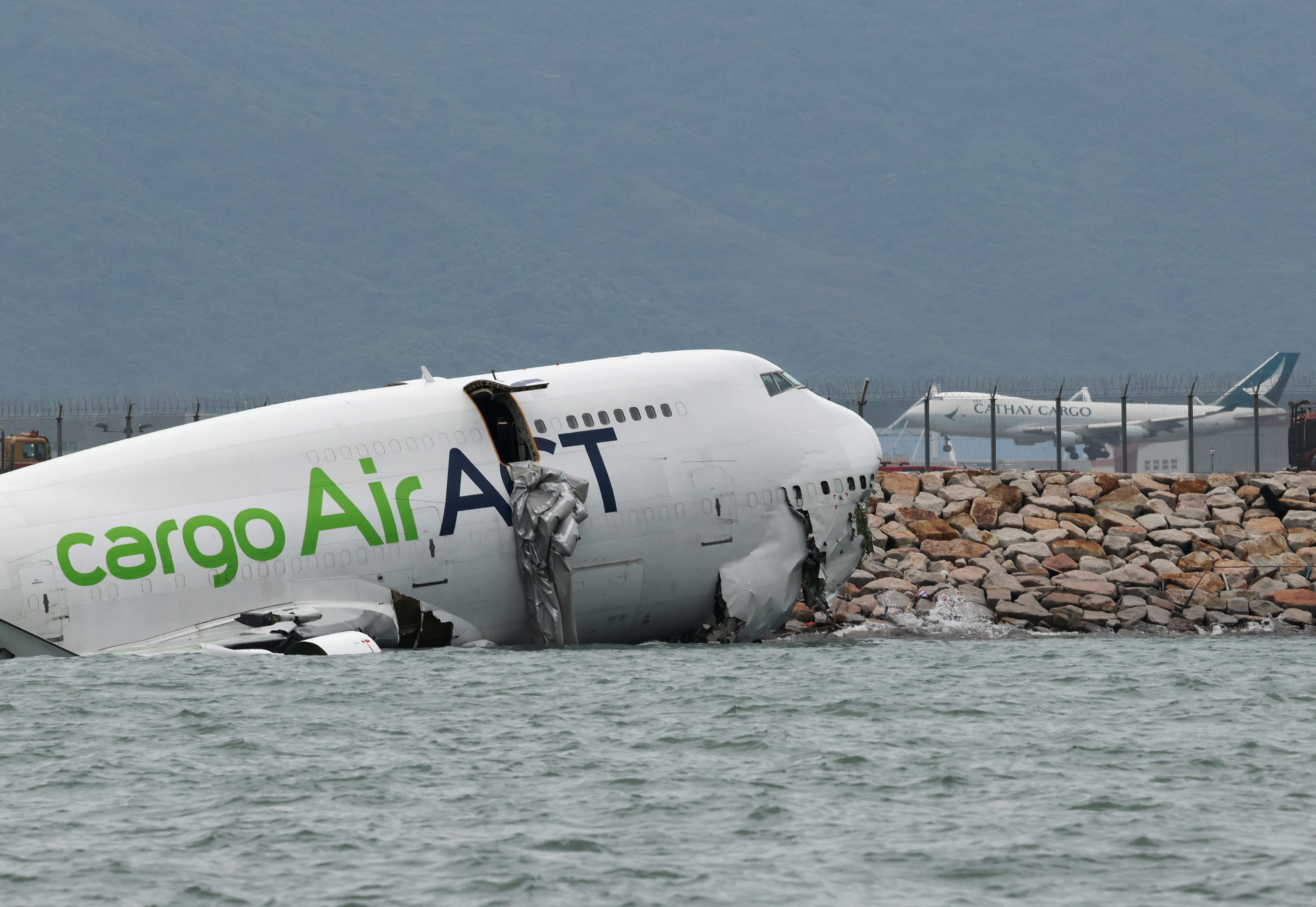 A cargo plane lies partially in the sea after veering off the runway during landing at Hong Kong International Airport in Hong Kong, China, October 20, 2025