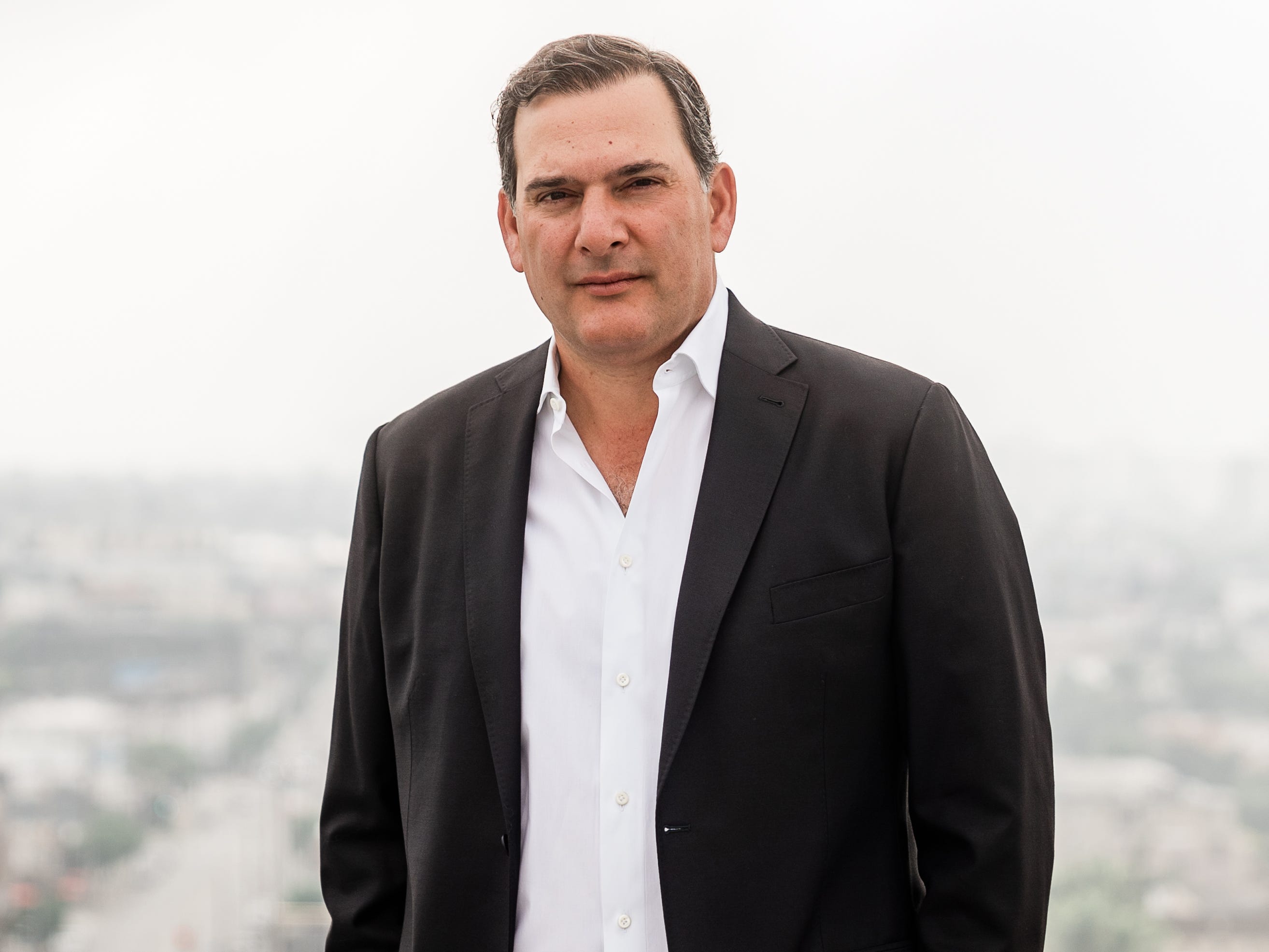 A man wearing a suit stands on a rooftop.