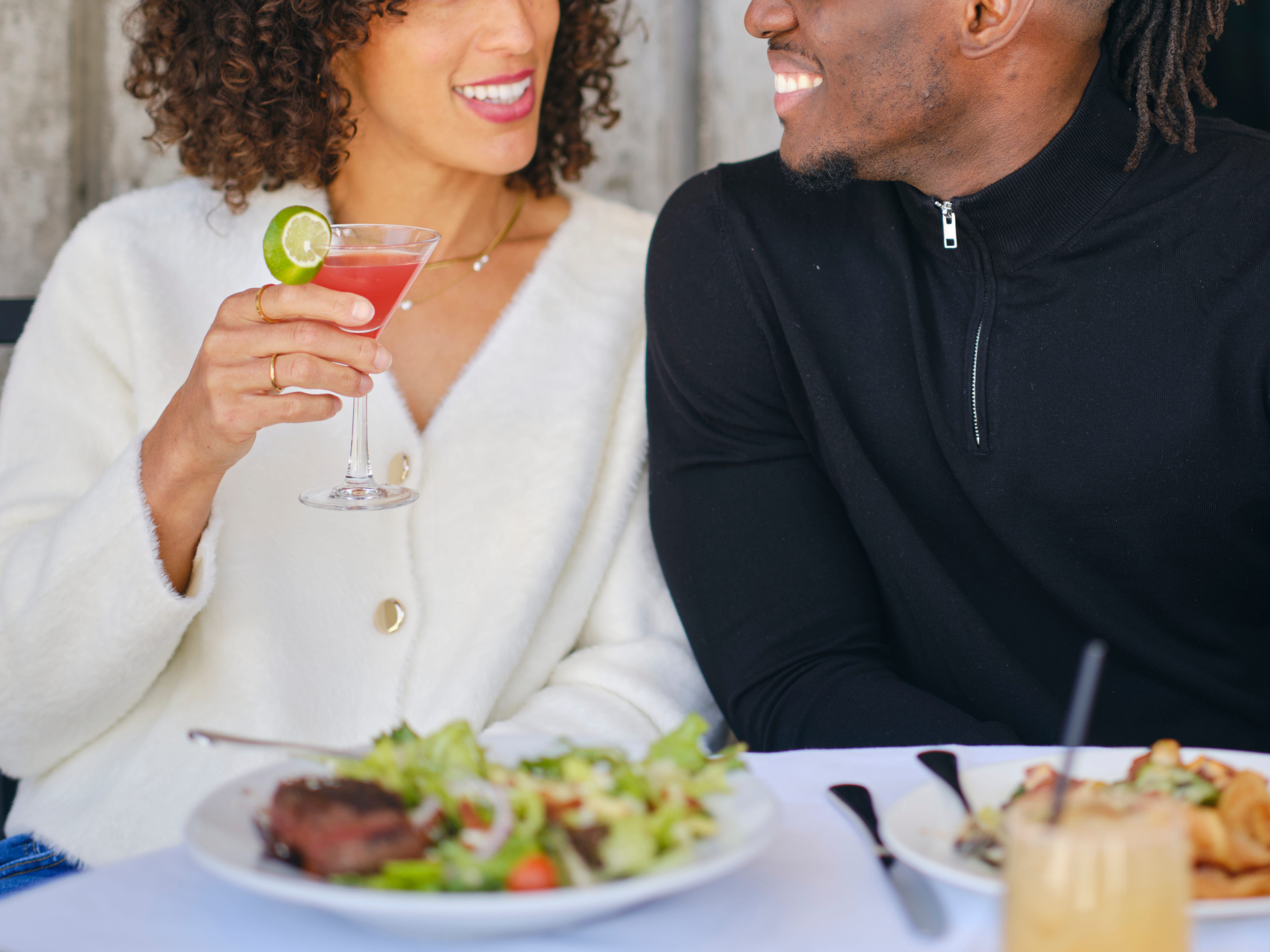 A man and woman smile at each other while sitting at a table in a restaurant.