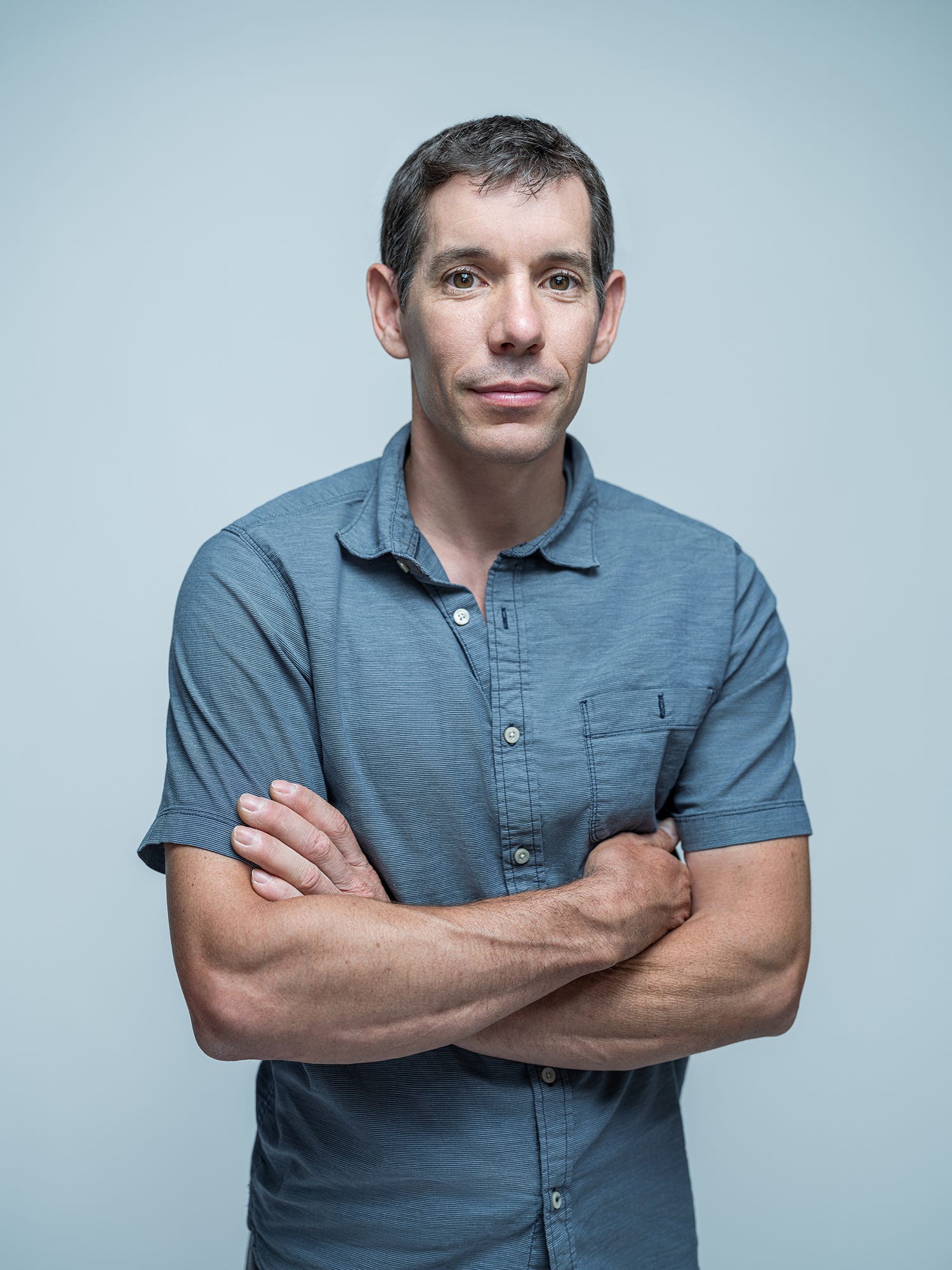 Alex Honnold standing with his arms crossed.
