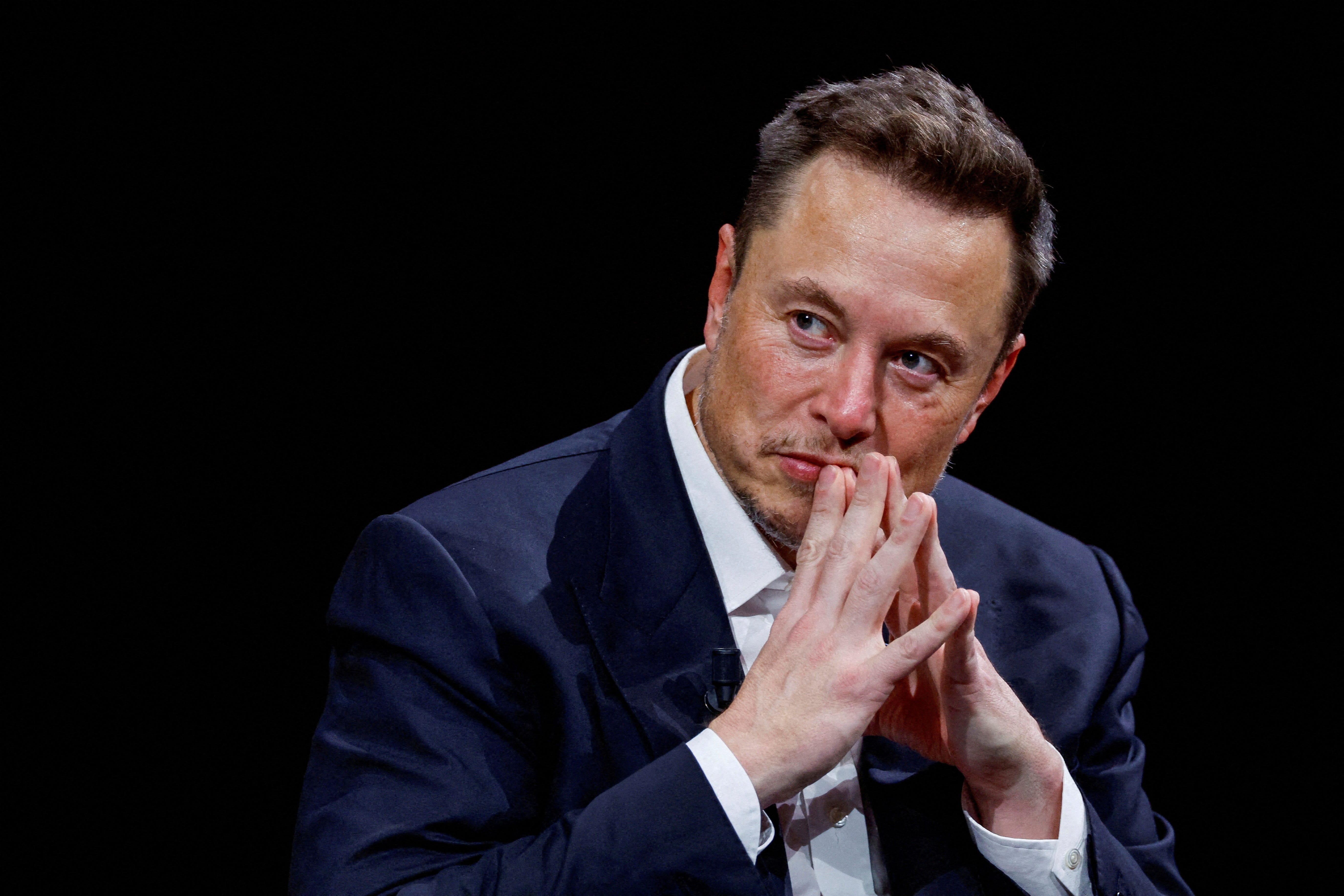 elon musk against black background making steeple gesture