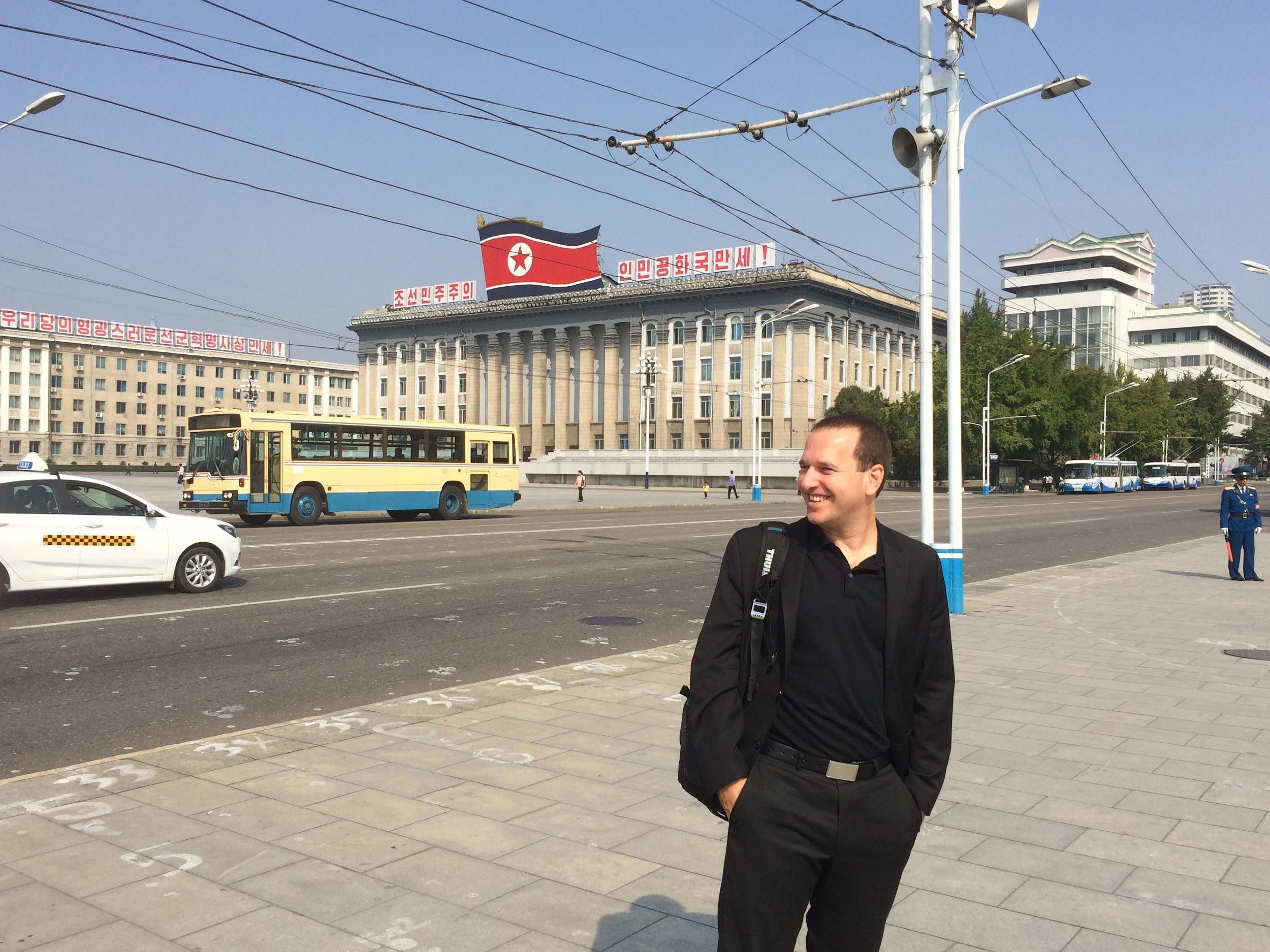 a man in black standing next to a busy street
