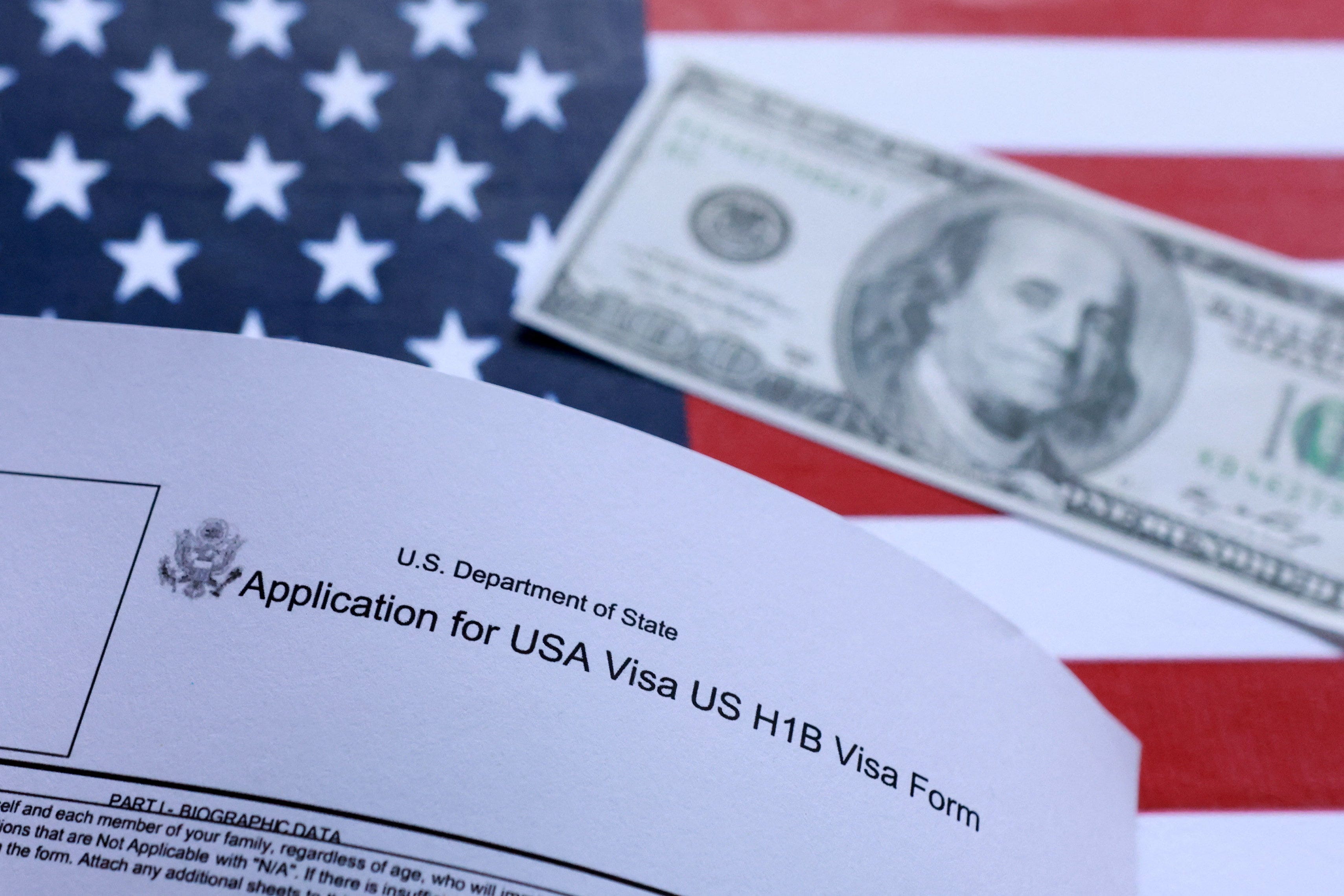 U.S. flag, mock passport, 100 dollar banknote and H-1B visa application form