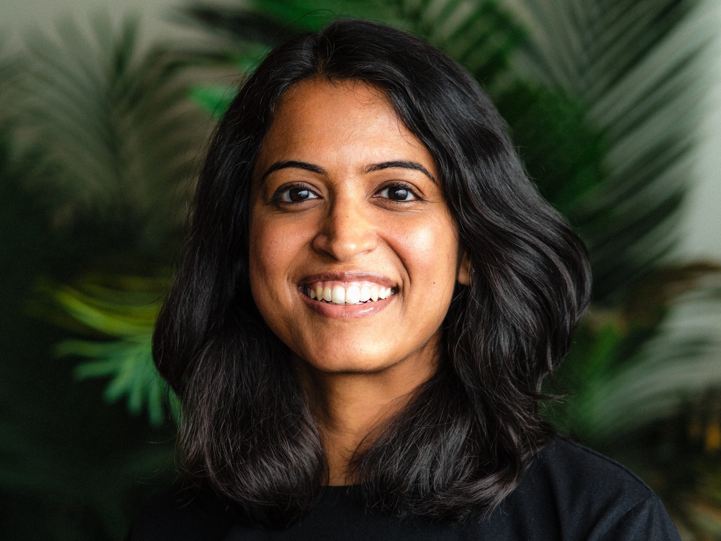 Priyanka Kulkarni smiles for a photo in front of a potted plant