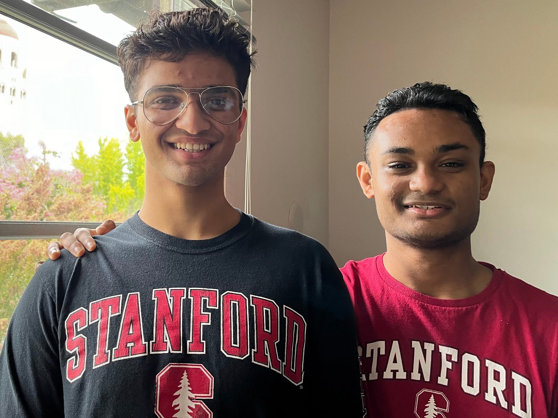 Shraman and Shreyas Kar, both wearing Stanford merch and posing next to a window.