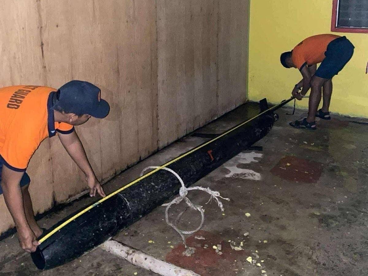 Members of the Philippine Coast Guard lifting up a 12-foot-long underwater drone made with Chinese labeling.