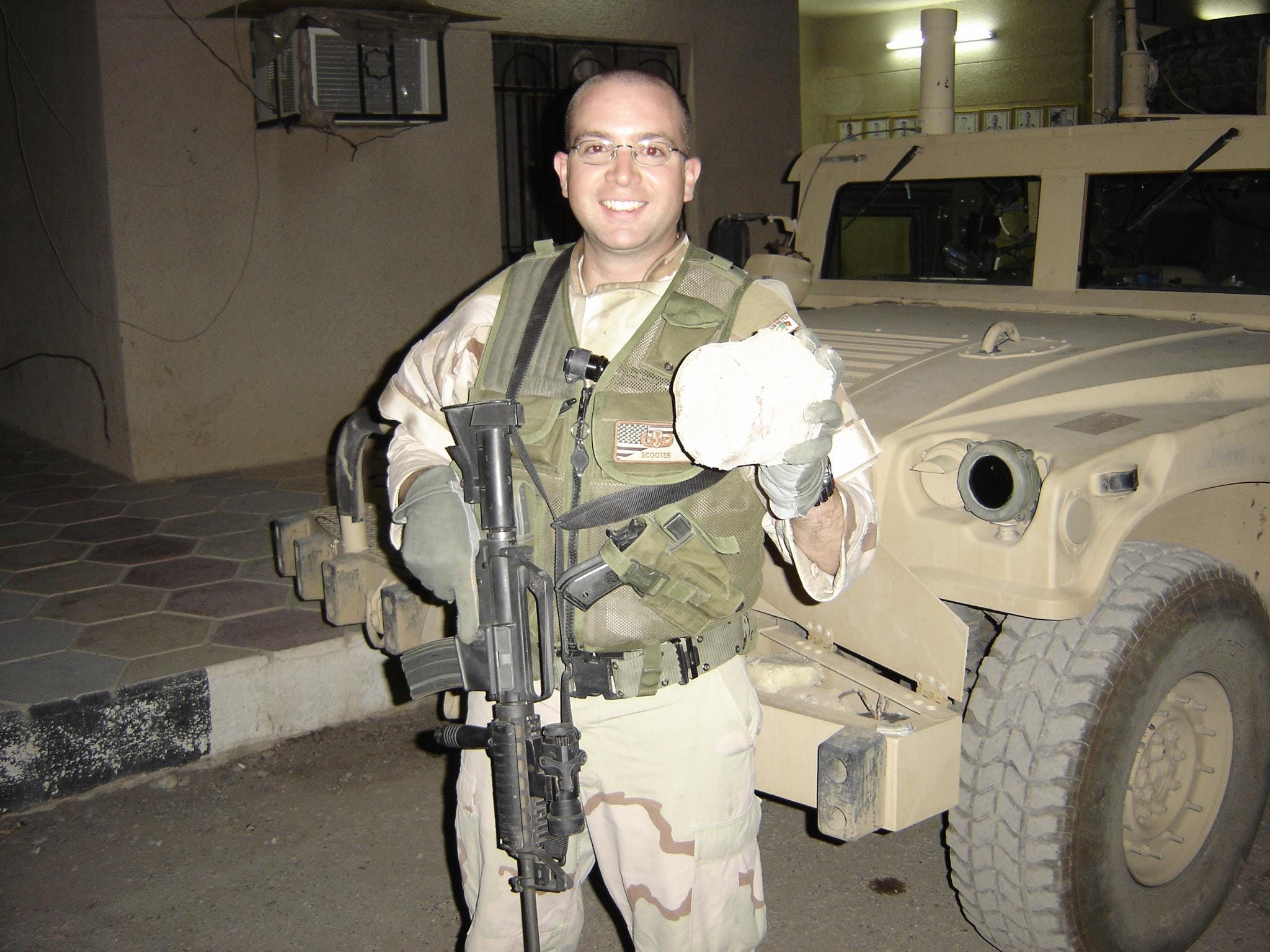 man in military gear holding a gun and what looks to be remnants of an explosive device