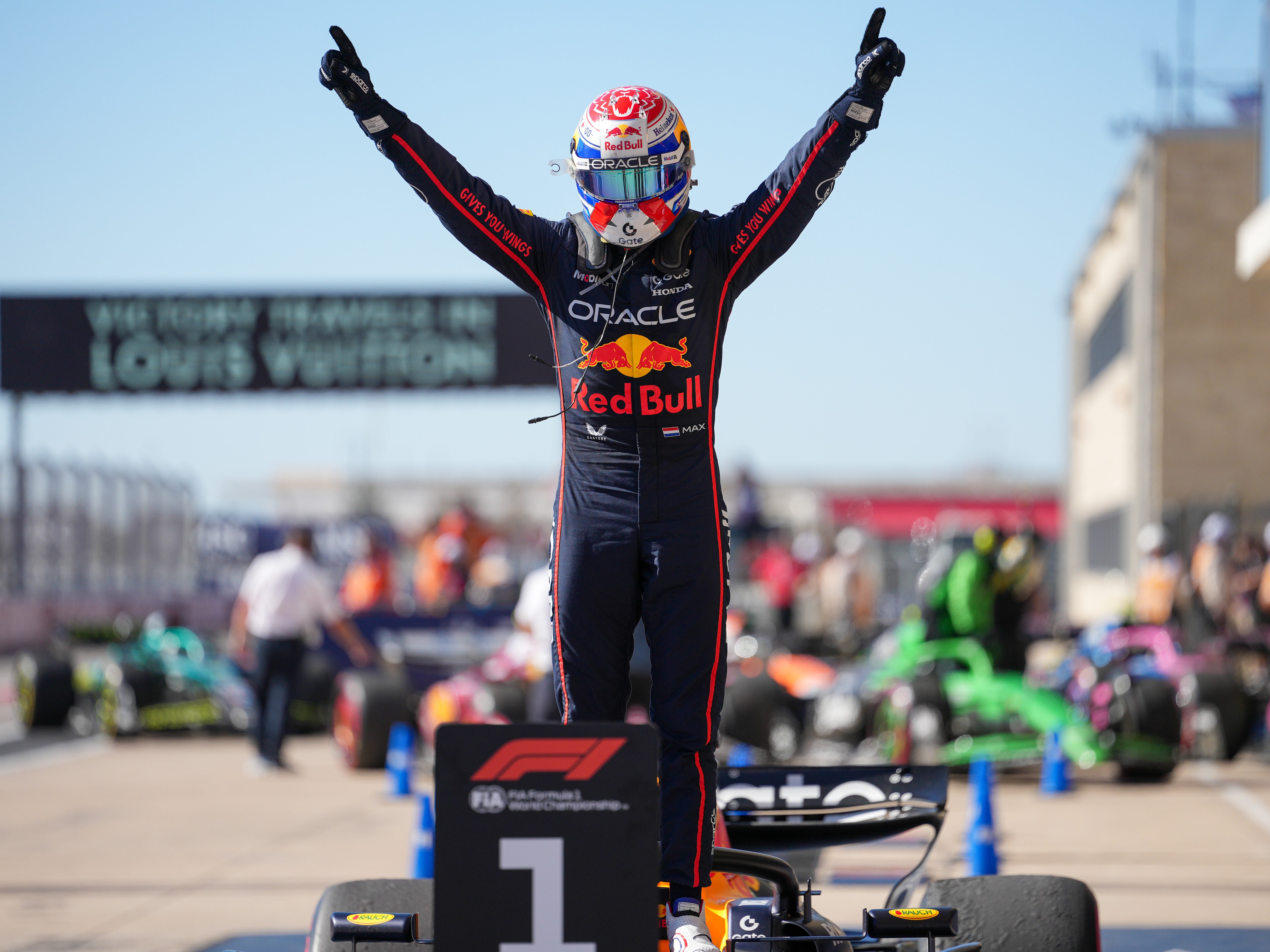 An F1 racer celebrates on top of his car.