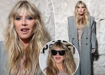 Heidi Klum pairs completely see-through lace dress with a platinum grill at Vetements show during Paris Fashion Week