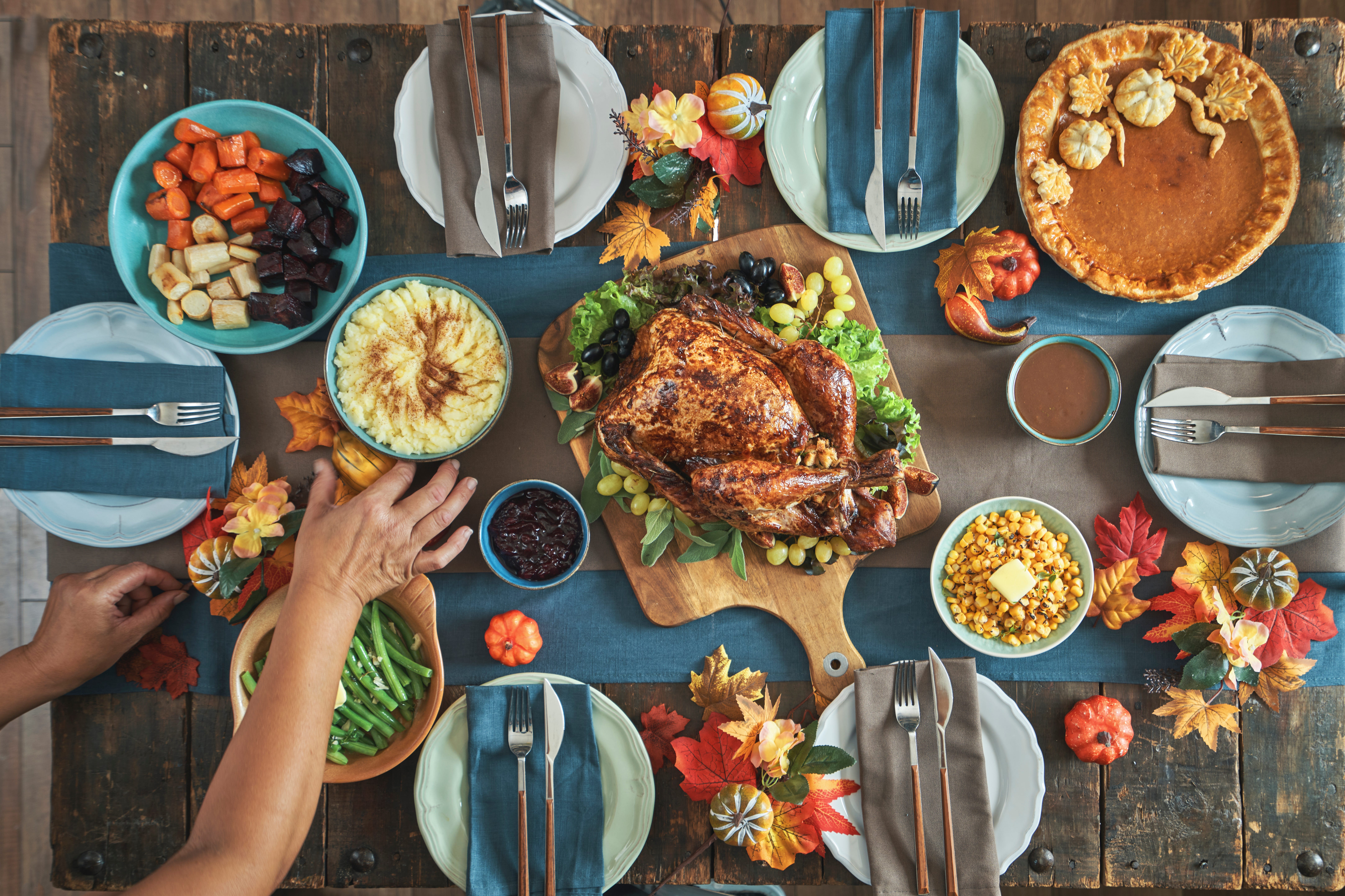 A table with Stuffed Turkey for Thanksgiving Holiday Dinner with Vegetables, Pumpkin Pie and Side Dishes