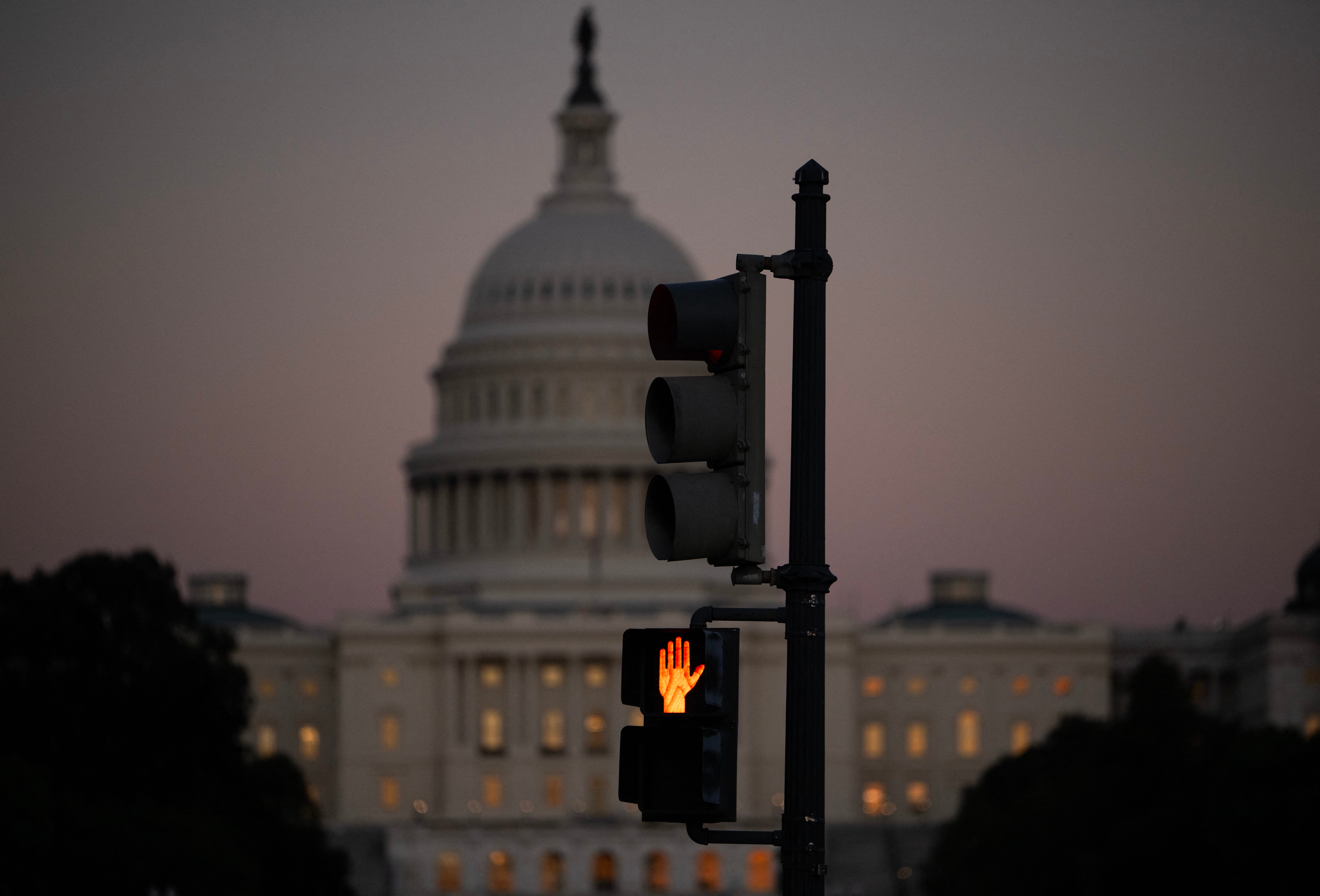 A crosswalk signal of a traffic light flashes backdropped by the US Capitol in Washington, DC, on October 1, 2025.
