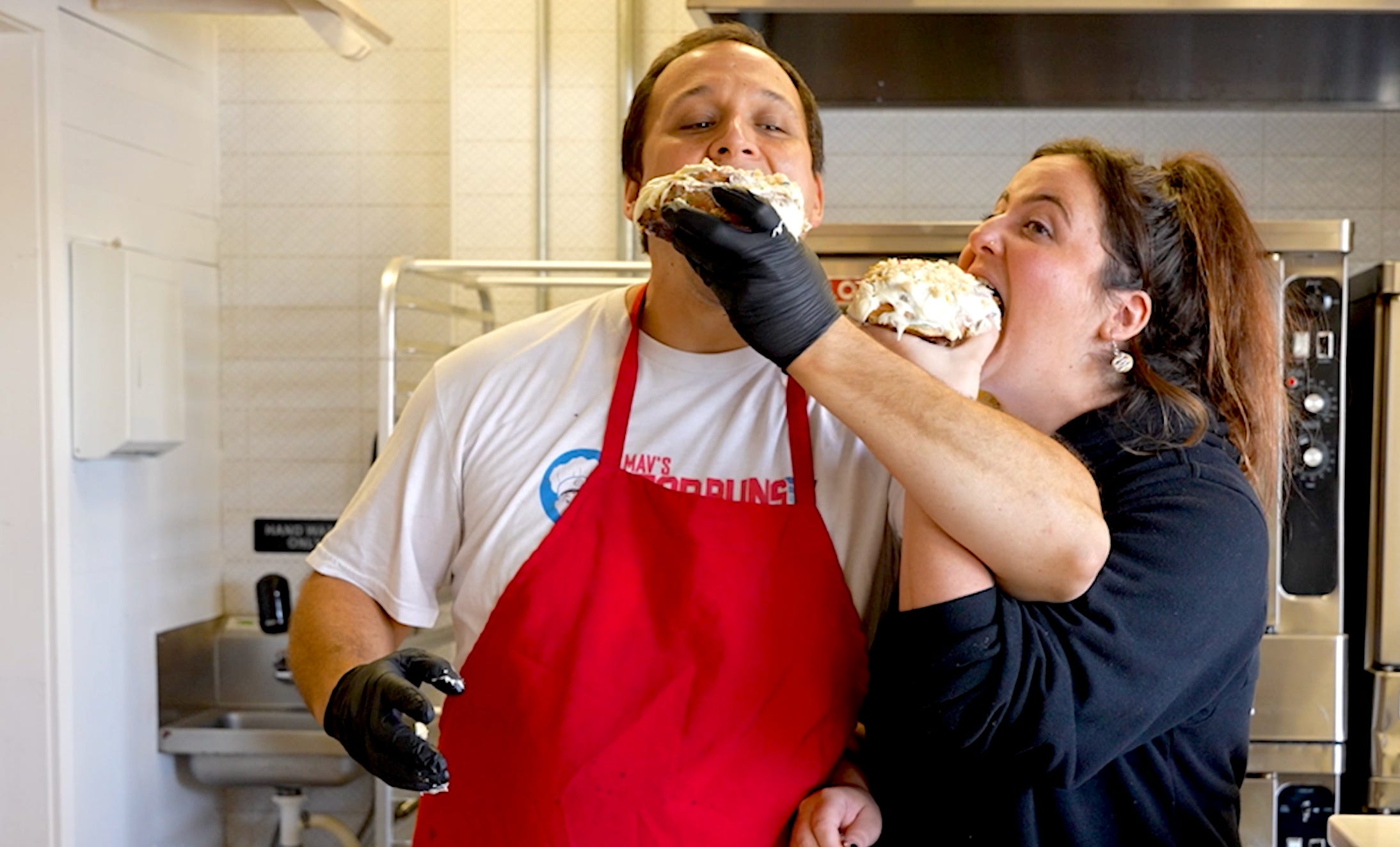 Husband and wife feeding each other cinnamon buns.