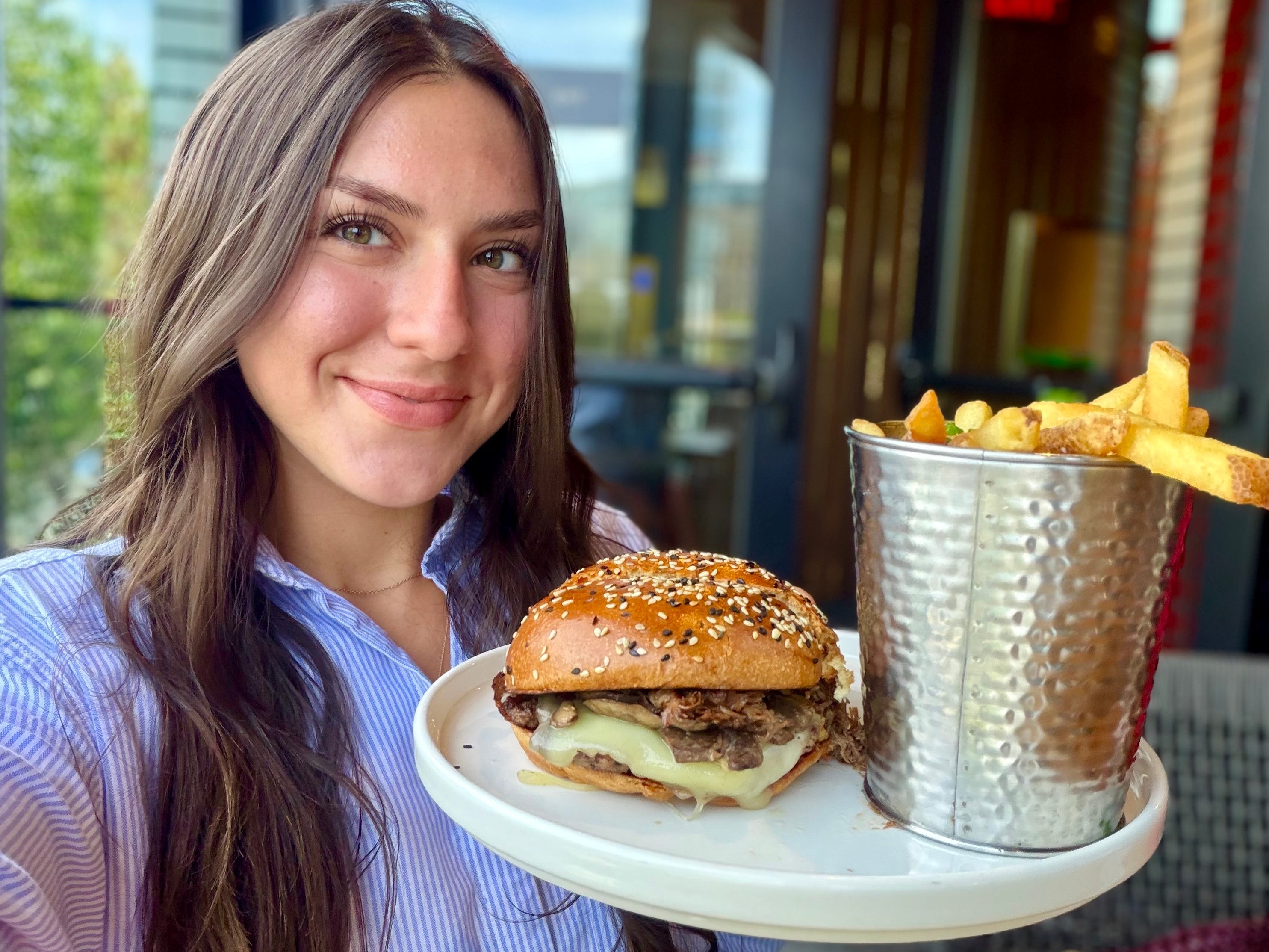 Amanda holding up a plate with a burger and fries.