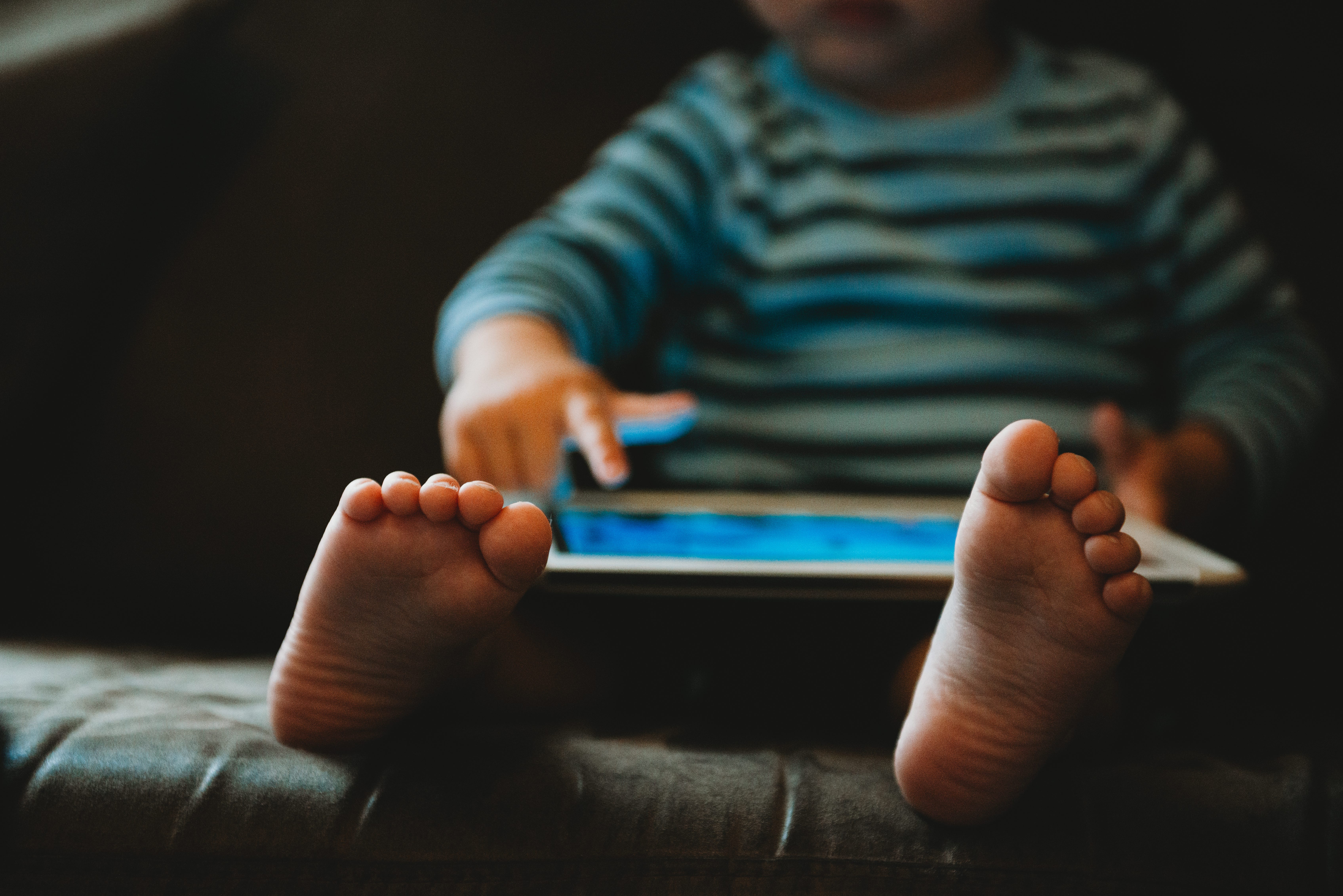 A young child is playing with a tablet during isolation in quarantine