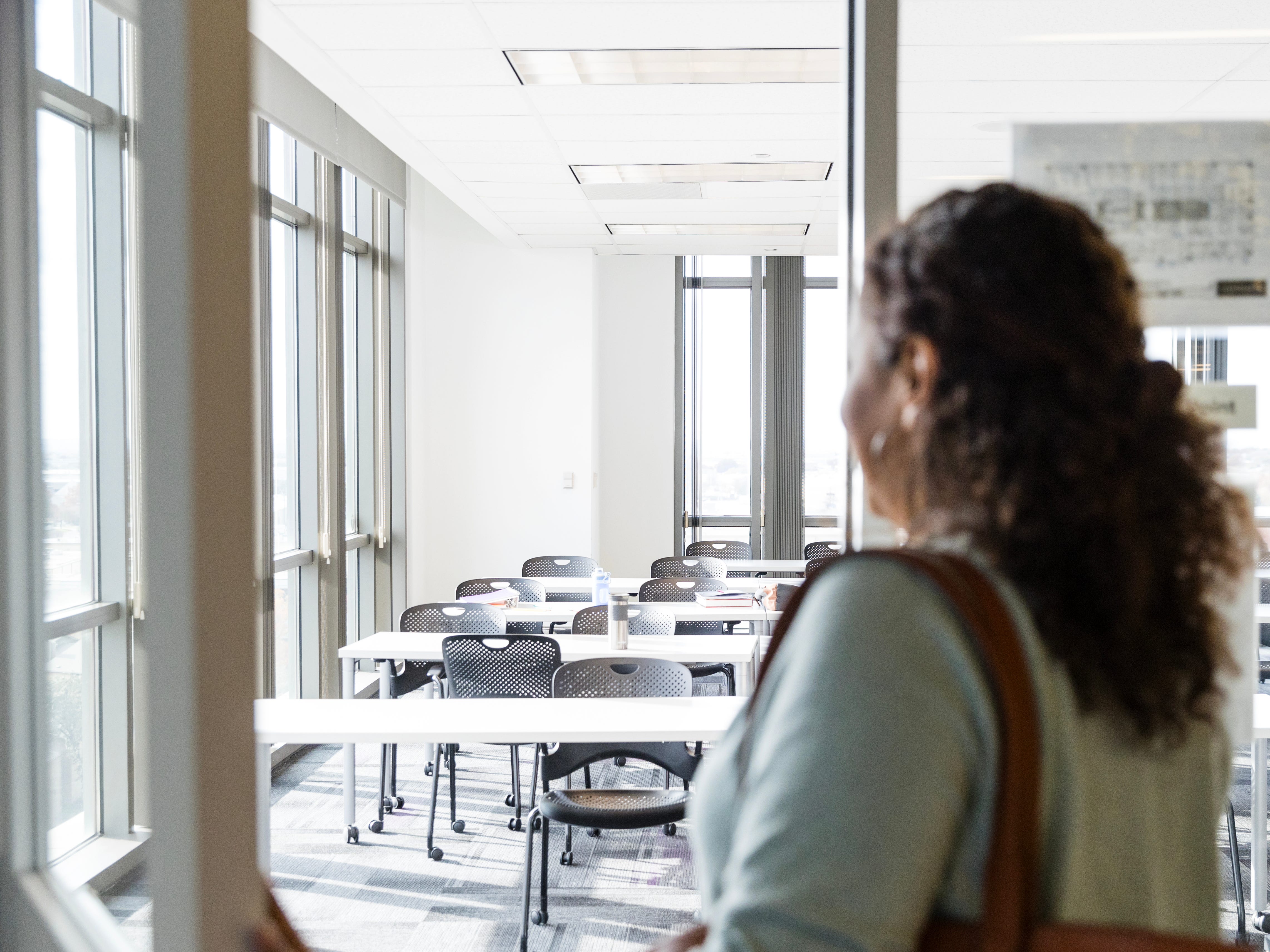 a woman entiering classroom with empty desks