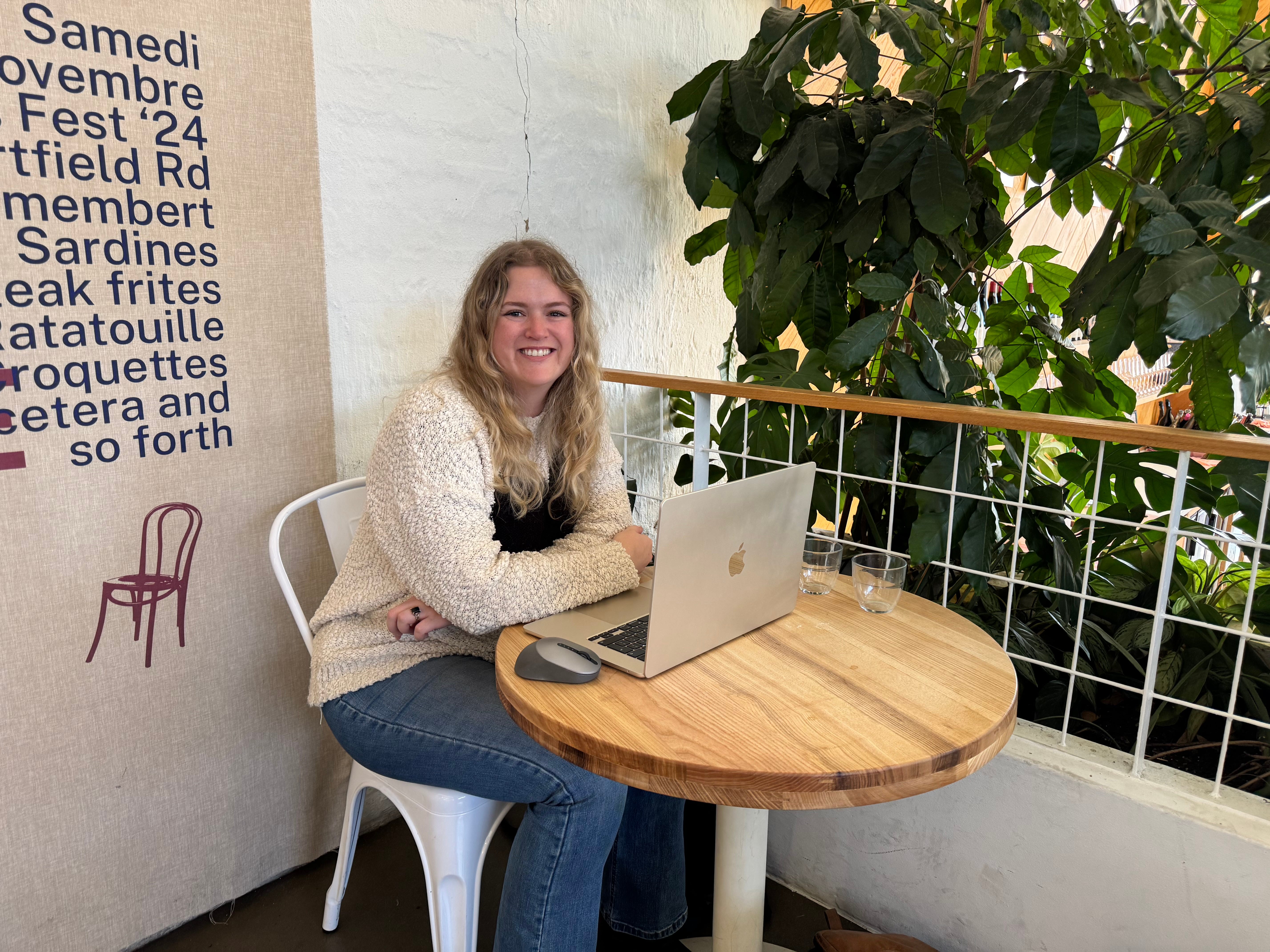 The author sitting at a table at a café with her laptop.
