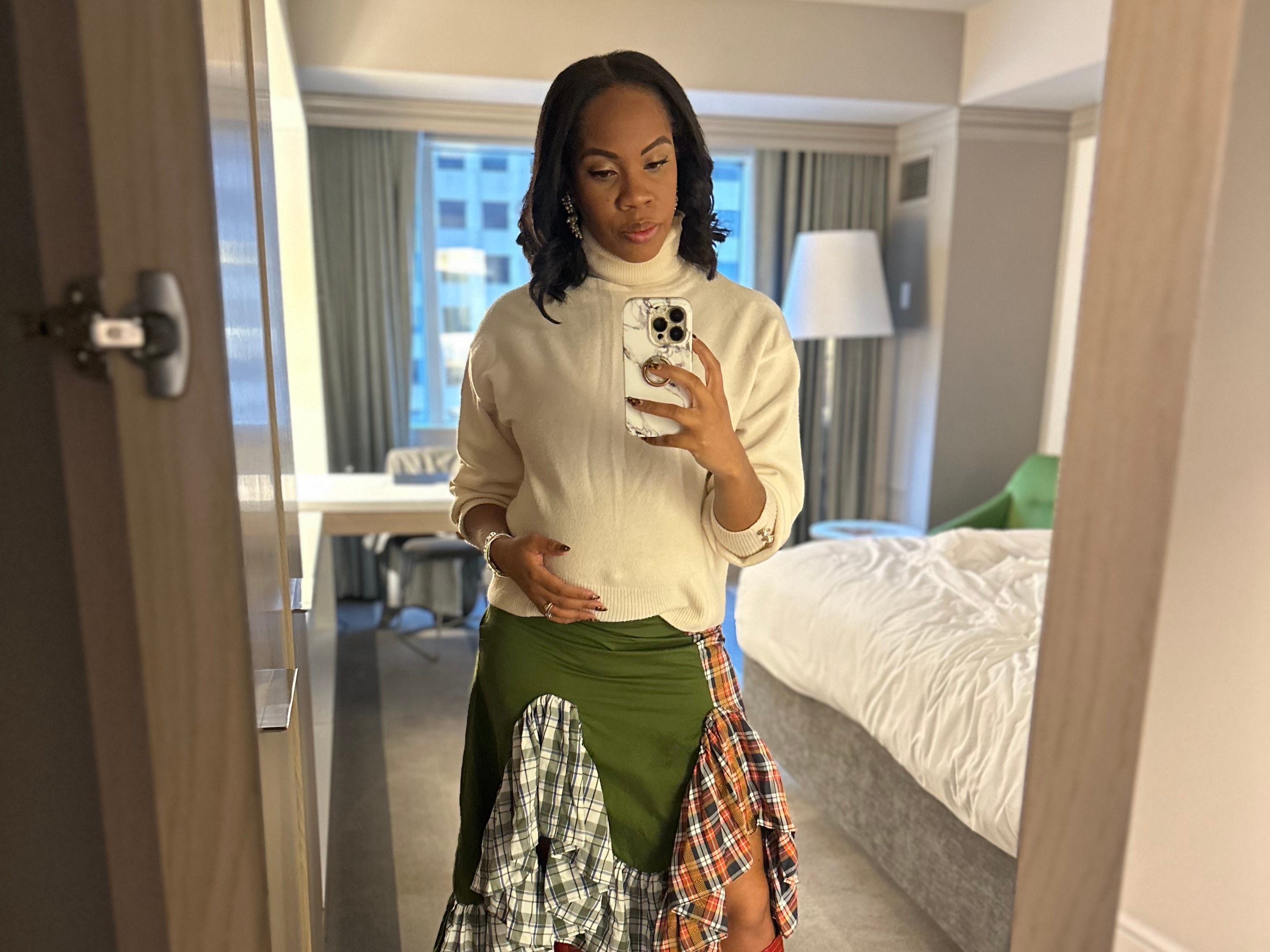 A woman taking a full-length selfie in the mirror