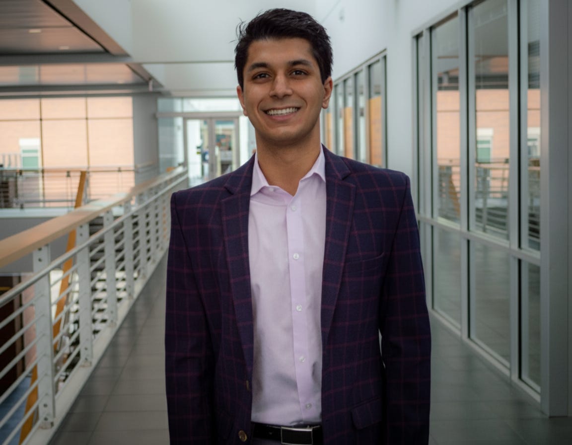 Varun Agarwal is wearing a chequered blazer on top of a pink shirt.