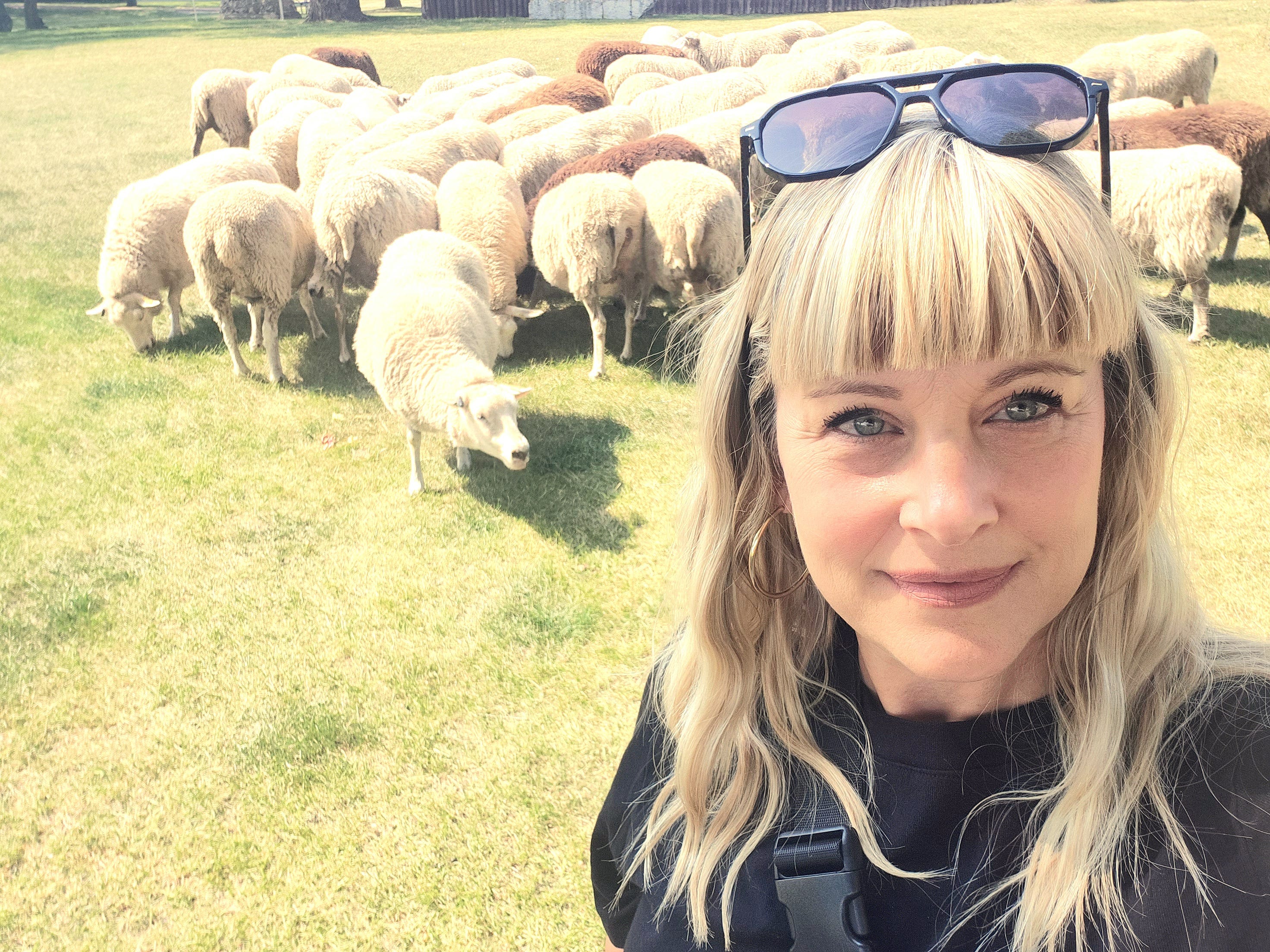Author Nicole Starker Campbell smiling with sheep behind her