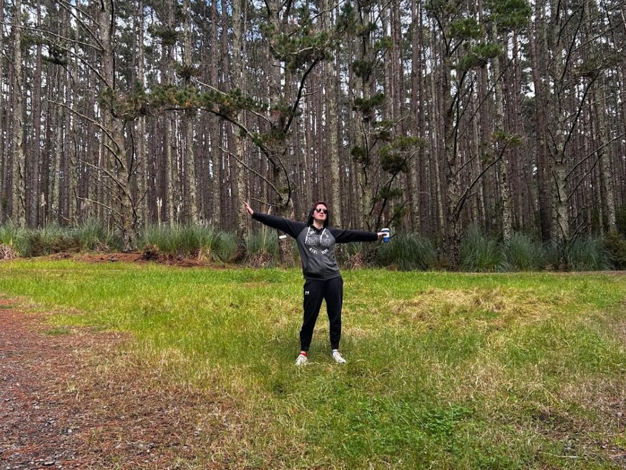 The writer standing in the woods near their new home in New Zealand's countryside.