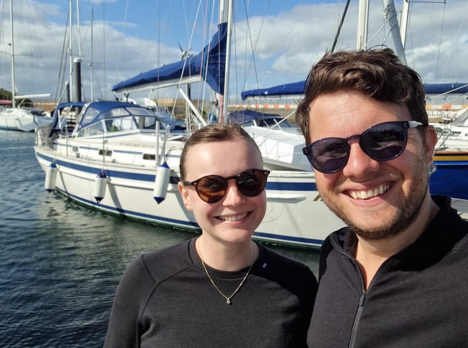 The writer and her partner in front of their sailboat.