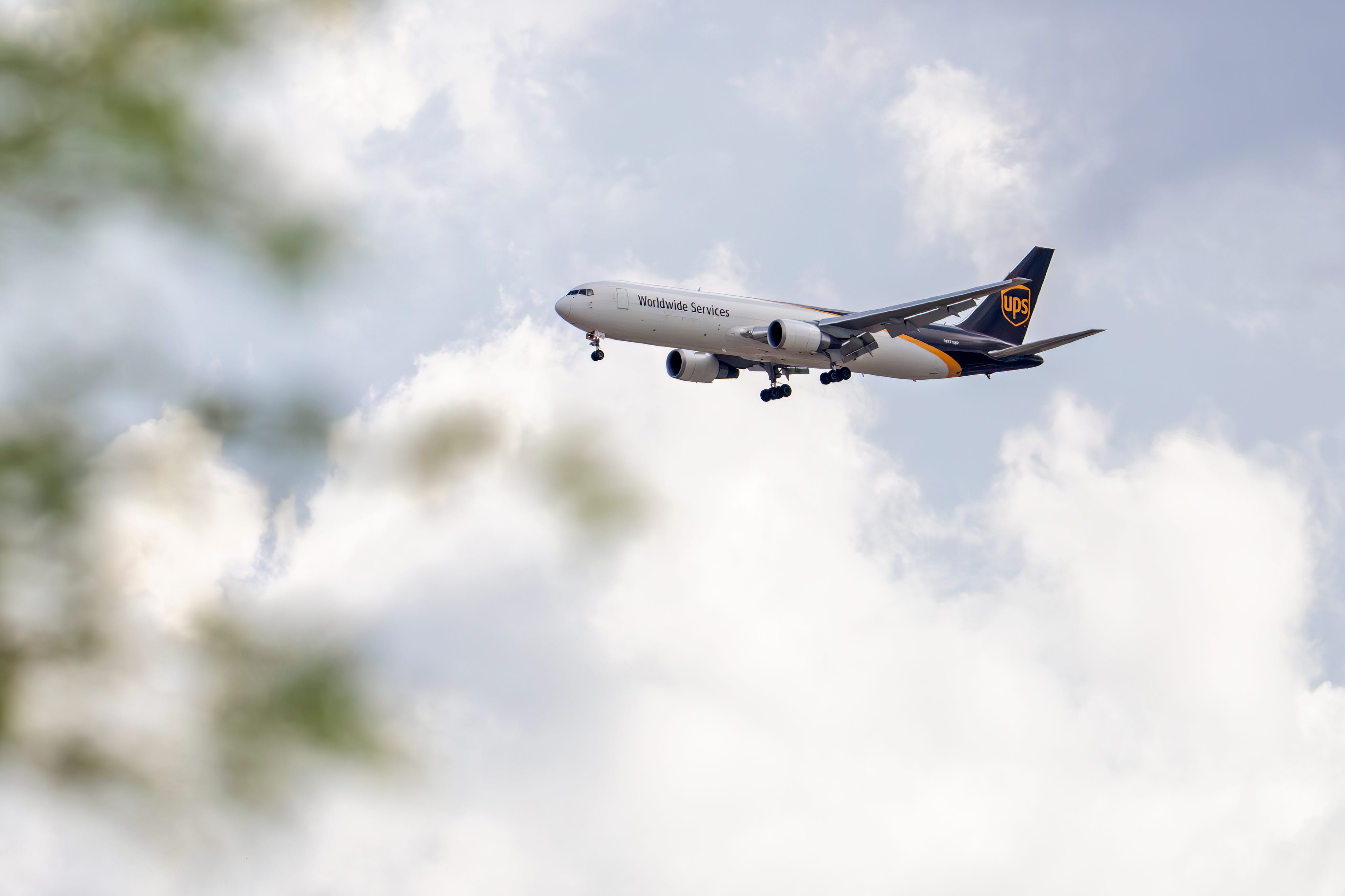 A UPS plane approaches an airport with its landing gear down and flaps extended.