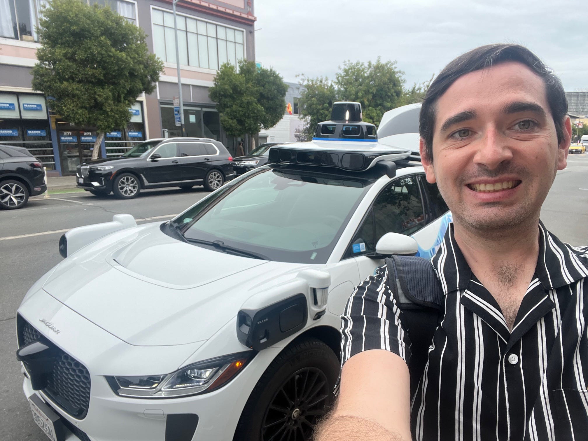 The author stands in front of a Waymo vehicle in San Francisco.
