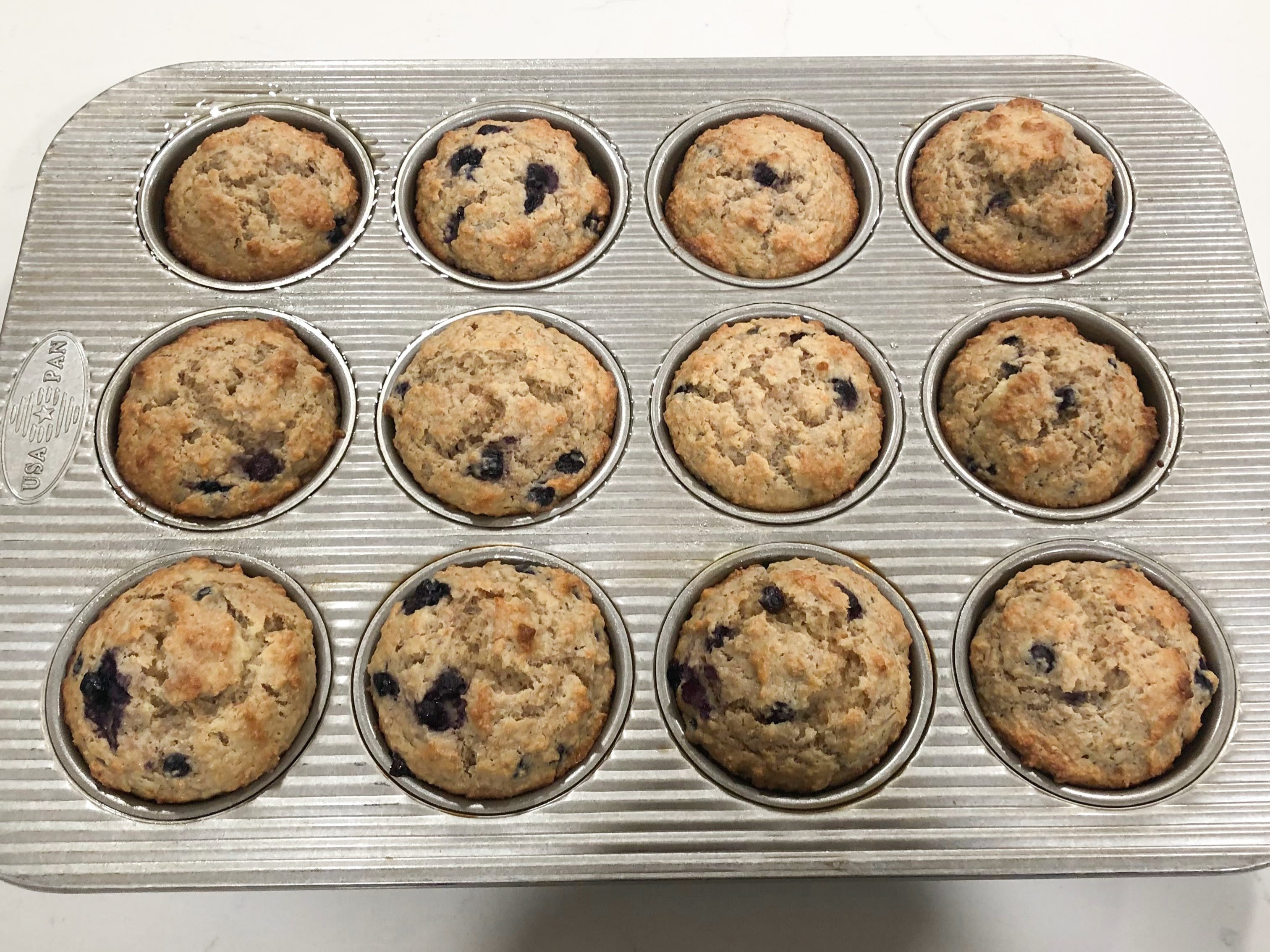 Cooked blueberry-bran muffins in a pan.