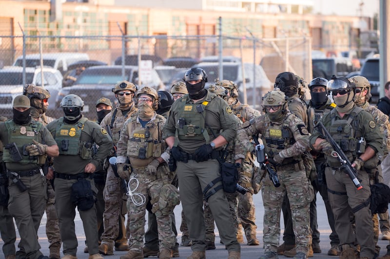 BROADVIEW, ILLINOIS - SEPTEMBER 27: U.S. Immigration and Customs Enforcement (ICE) agents, Department of Homeland Security (DHS) personnel, and Border Patrol Commander Gregory Bovino stand together amidst a tense protest outside the ICE processing facility in Broadview, Illinois, on September 27, 2025. Demonstrators gathered to oppose the Trump administration's immigration enforcement operations, including 'Operation Midway Blitz,' as clashes escalated with reports of tear gas and pepper balls used to disperse crowds.