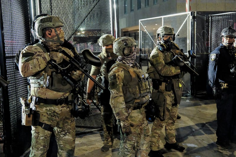 Police in riot gear and armed officers stand guard outside the Metropolitan Detention Center in Los Angeles