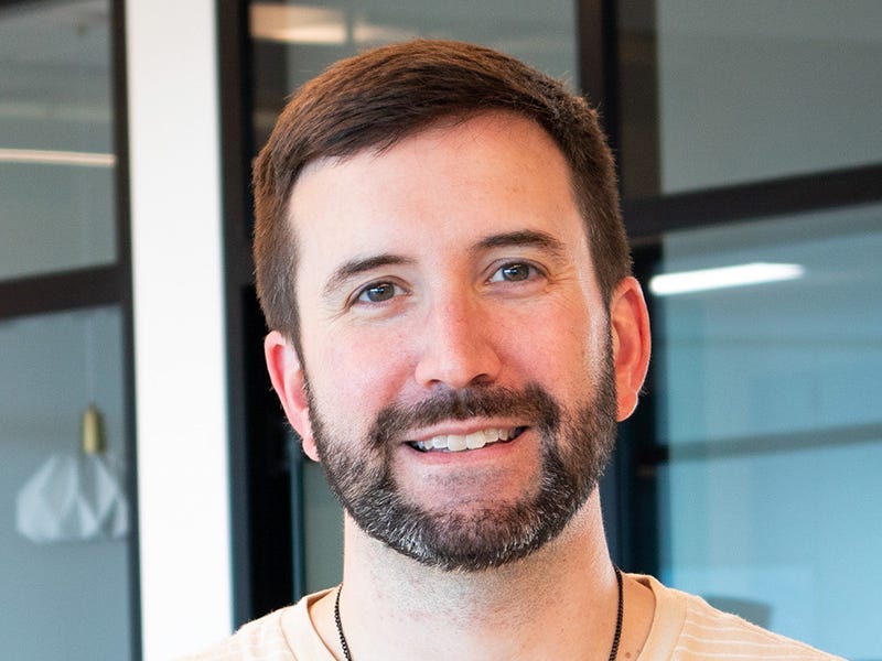 headshot of a man in a striped yellow shirt