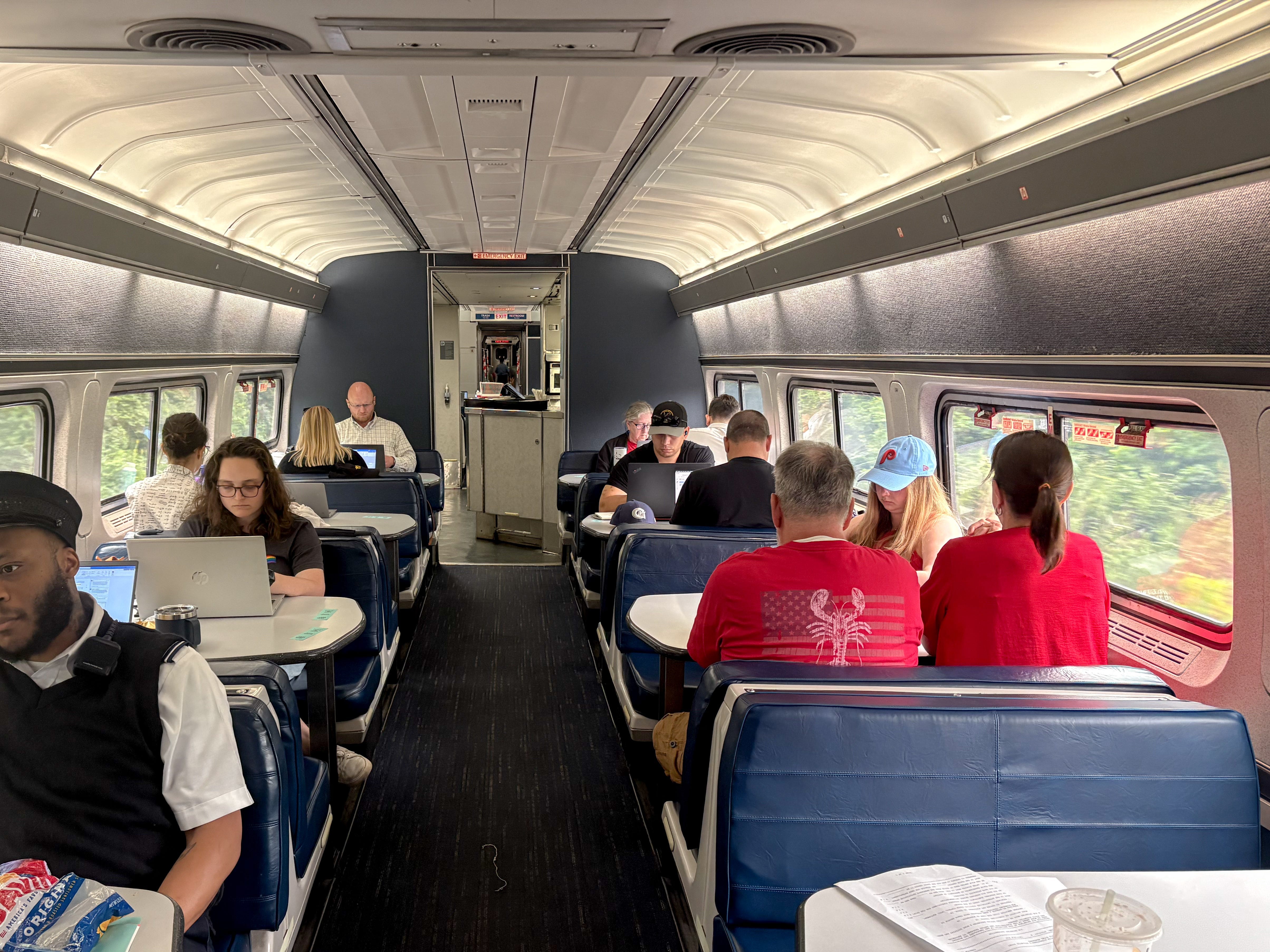 People sitting in booth-style seats on an Amtrak train.